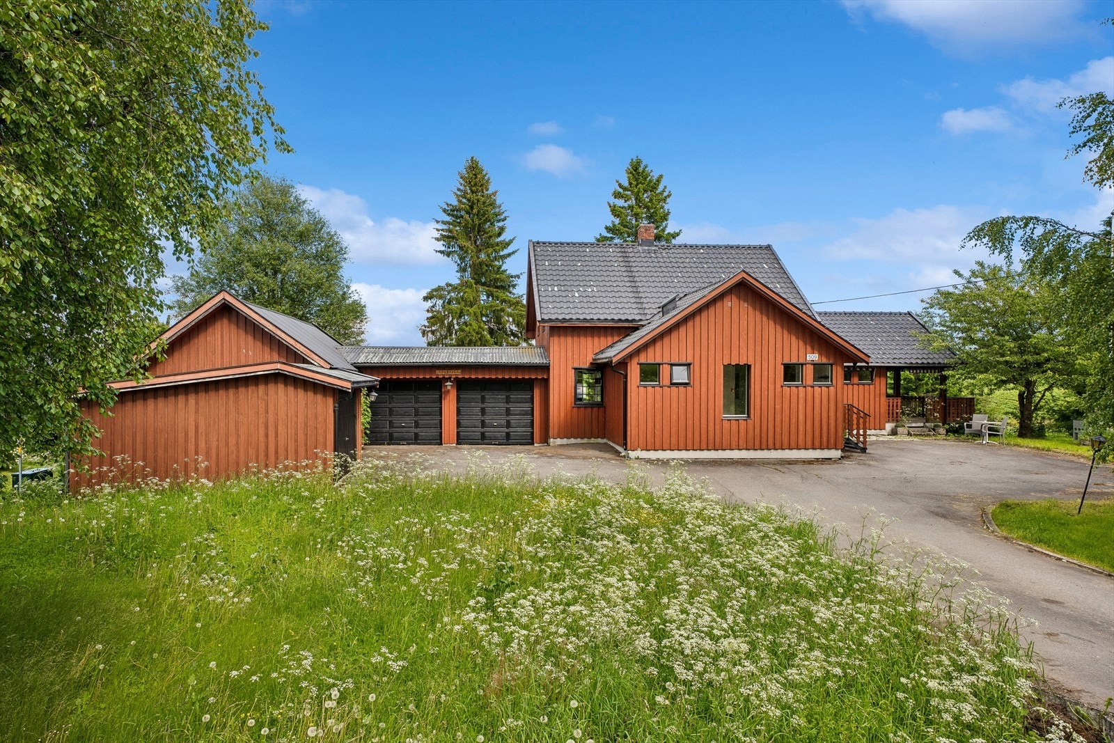 Asfaltert gårdsplass med parkering i to garasjer. Galleribilde