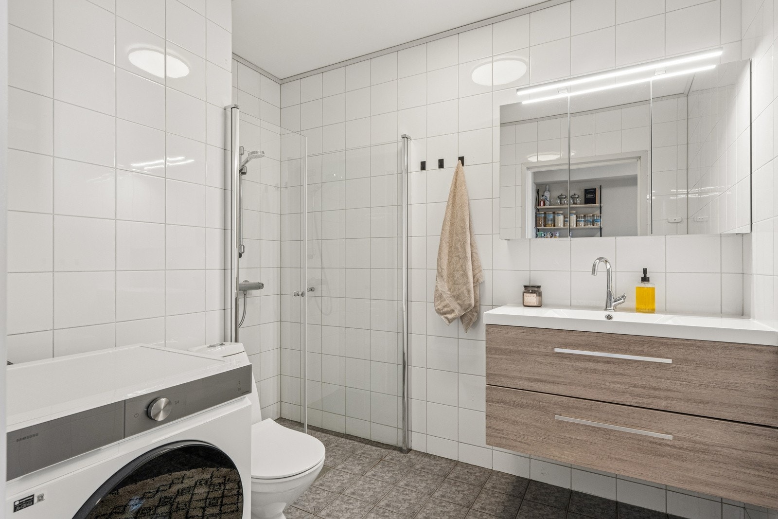 Flislagt og romslig baderom med plass til vaskemaskin.