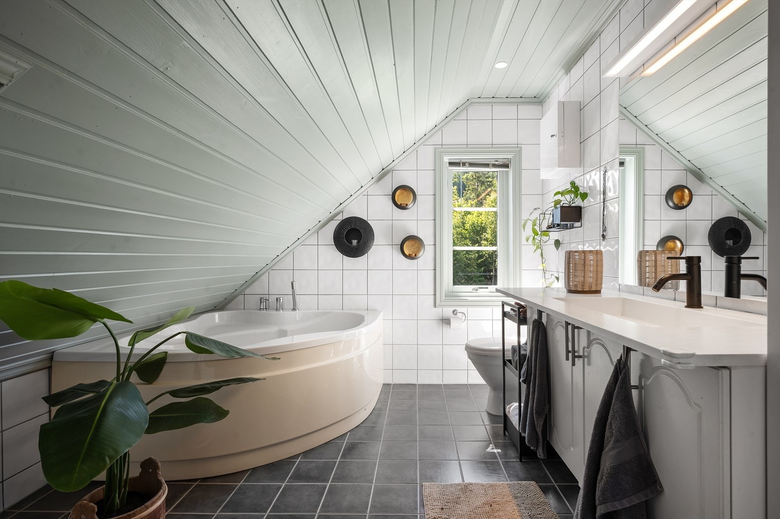 Badet er innredet med toalett, baderomsinnredning, hjørnebadekar og dusjnisje med regnfallsdusj Galleribilde