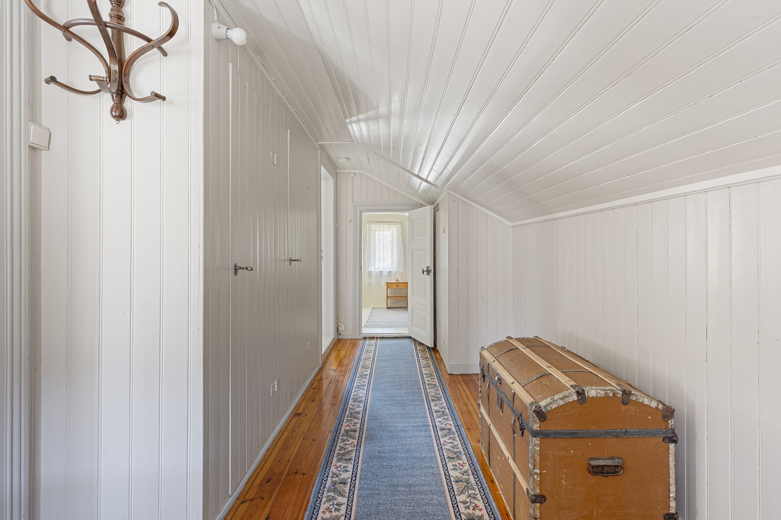 Koselig gang med god plass til oppbevaring i innebygde skap. I enden av gangen er det et lite soverom. Galleribilde