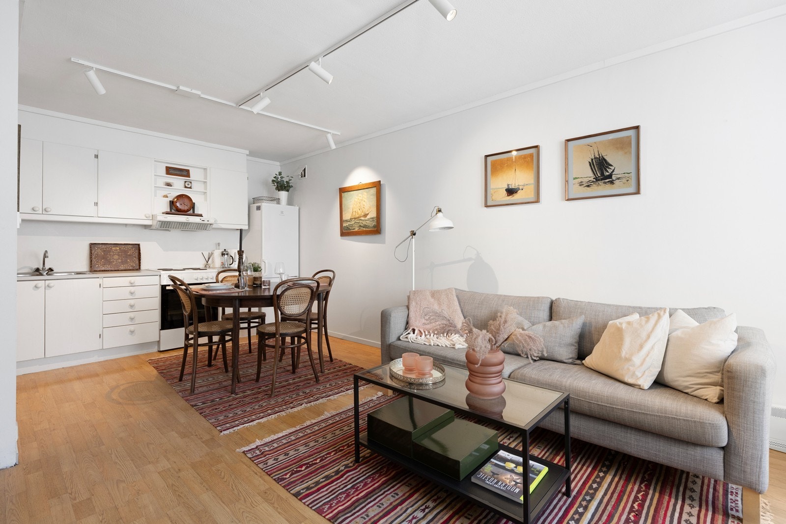 Stuen er pent innredet med 3-seters sofa og spisebord med stoler i kjøkkensonen. Galleribilde