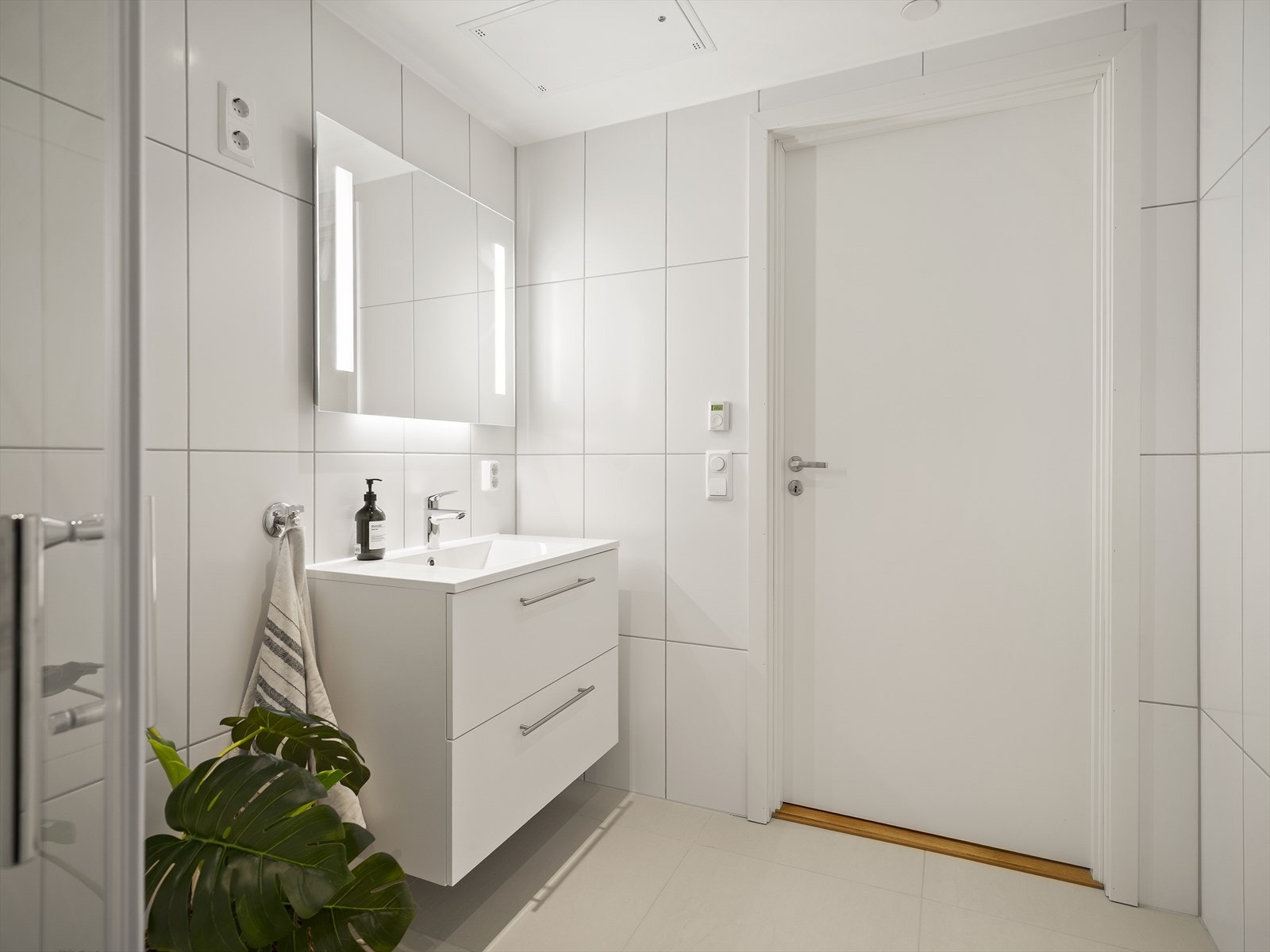 Bad/vaskerom med lyse fliser og downlights Galleribilde