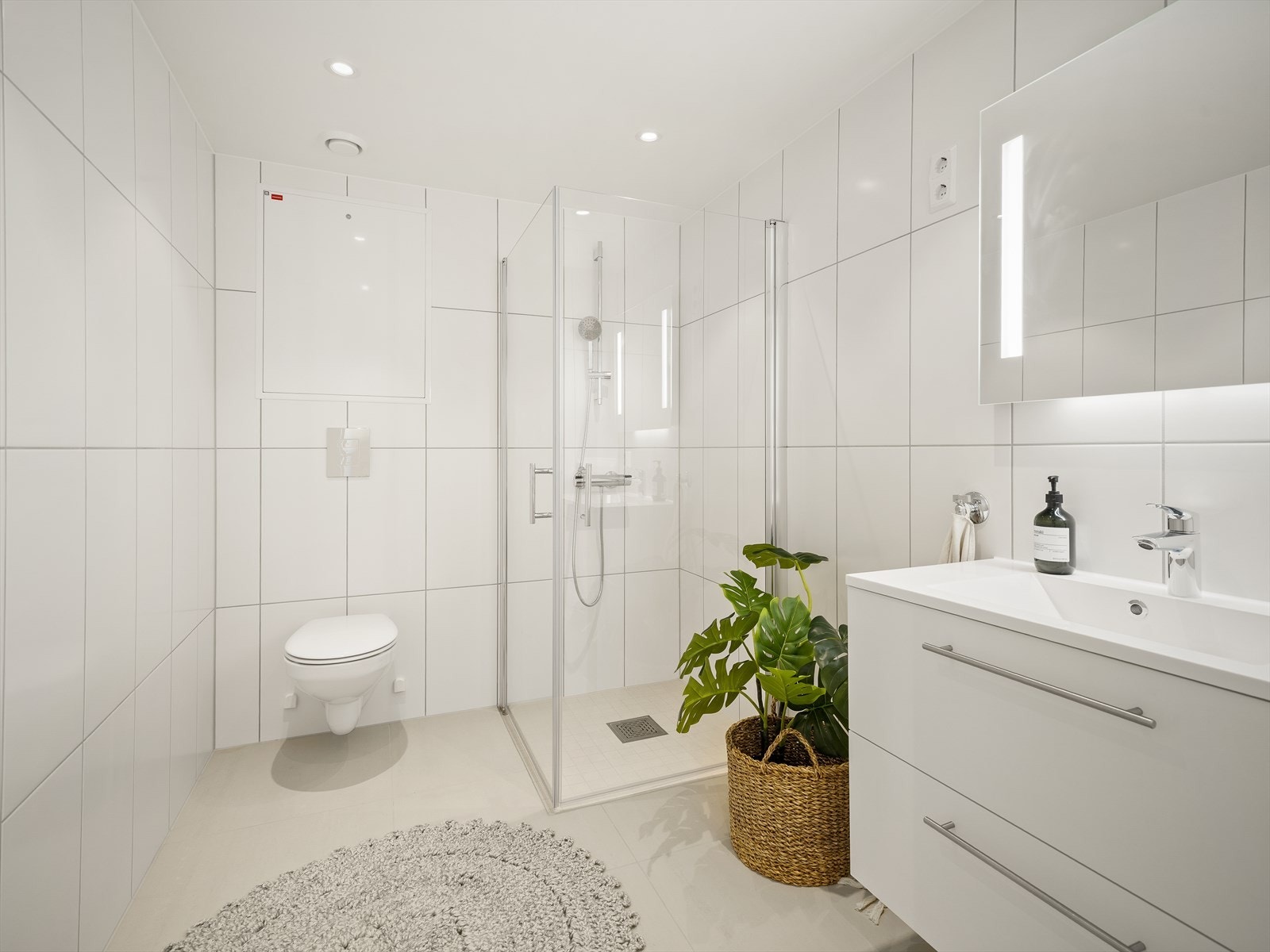 Bad/vaskerom med lyse fliser og downlights Galleribilde