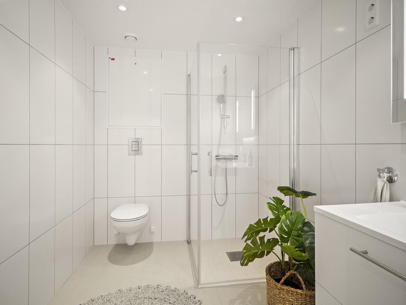 Bad/vaskerom med lyse fliser og downlights Galleribilde
