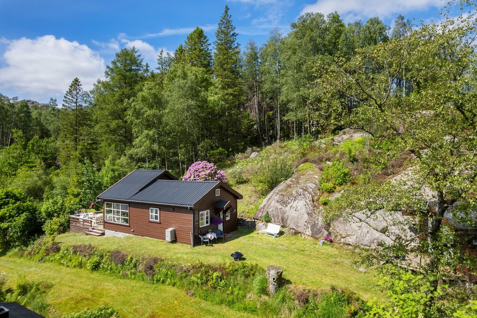 Hytta ligger fint til i et lite hytteområde, omkranset av natur. Galleribilde