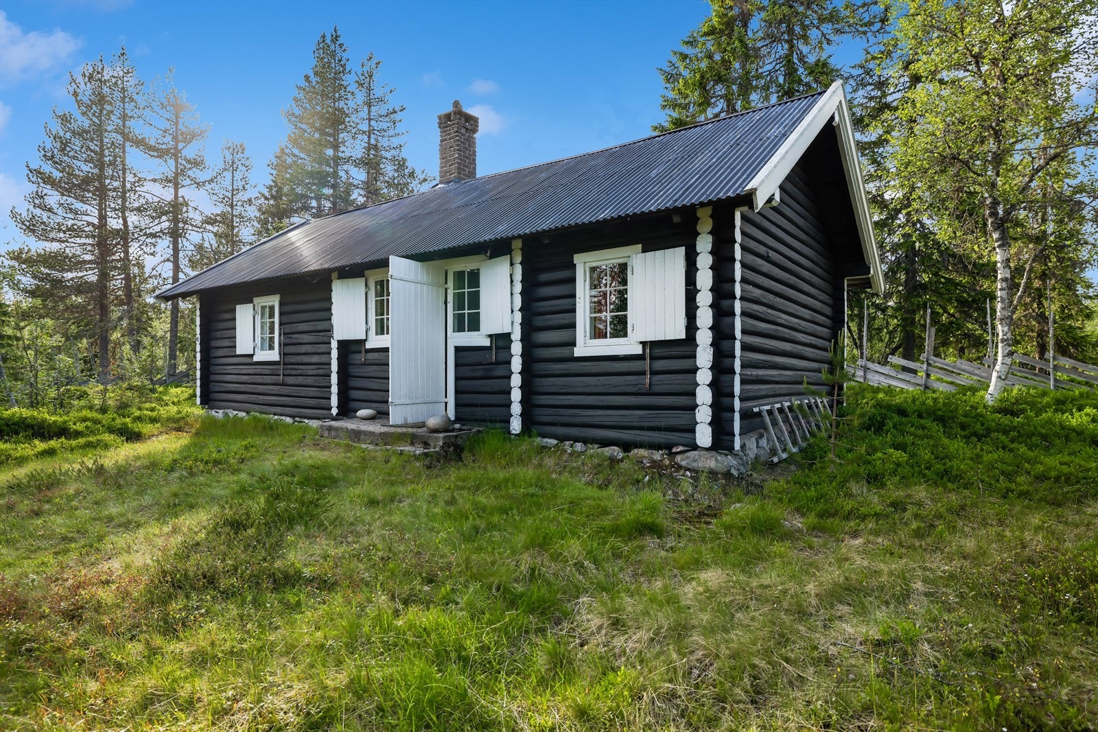 Tradisjonsrik seterhytte med sortmalt fasade, hvite detaljer og enkel fjellstandard. Galleribilde