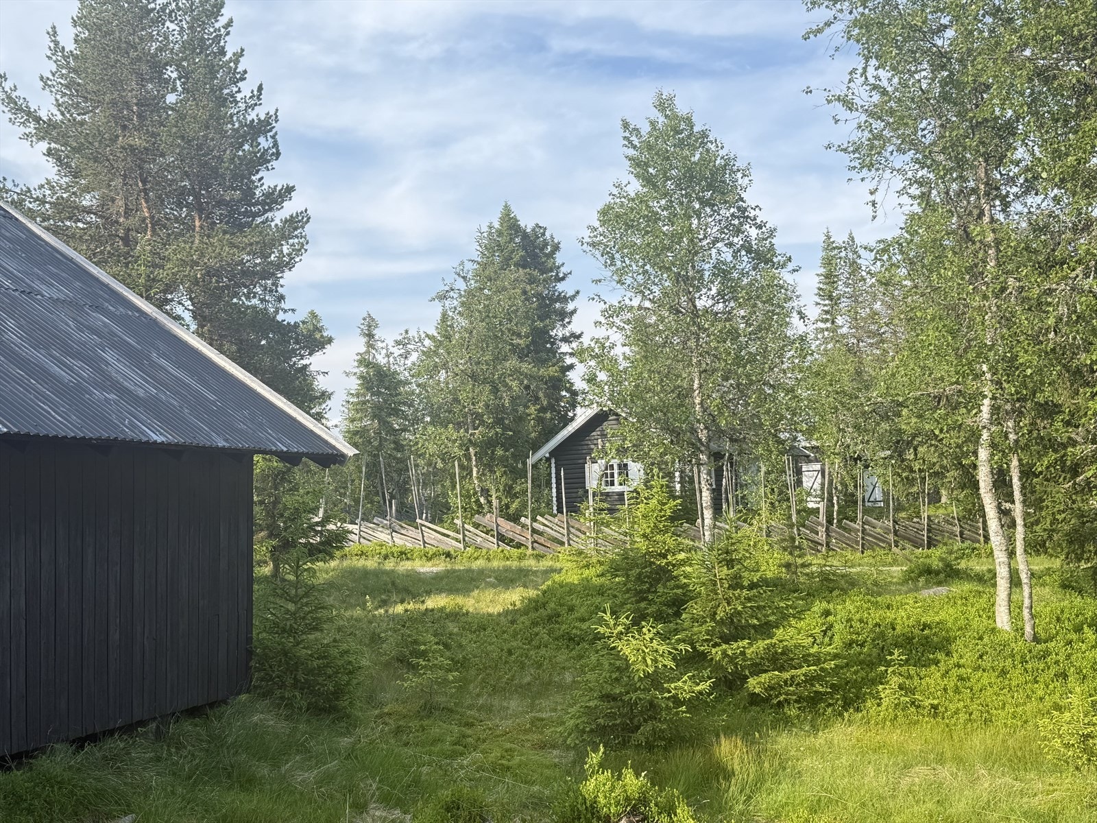 Østre Fjellvegen går rett forbi eiendommen, med hytte og låve/bod på hver sin side av veien. Galleribilde