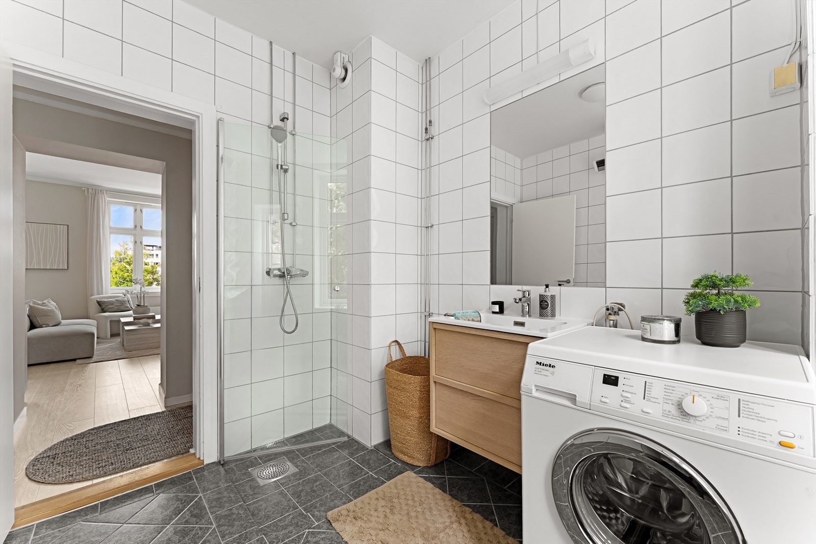 Badet har et nedsenket dusjhjørne med glassdør og opplegg for vaskemaskin. Galleribilde