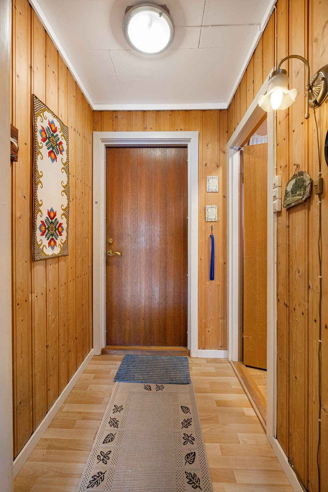 Inngangspartiet ønsker velkommen med panelkledde vegger og laminat på gulvet. Galleribilde
