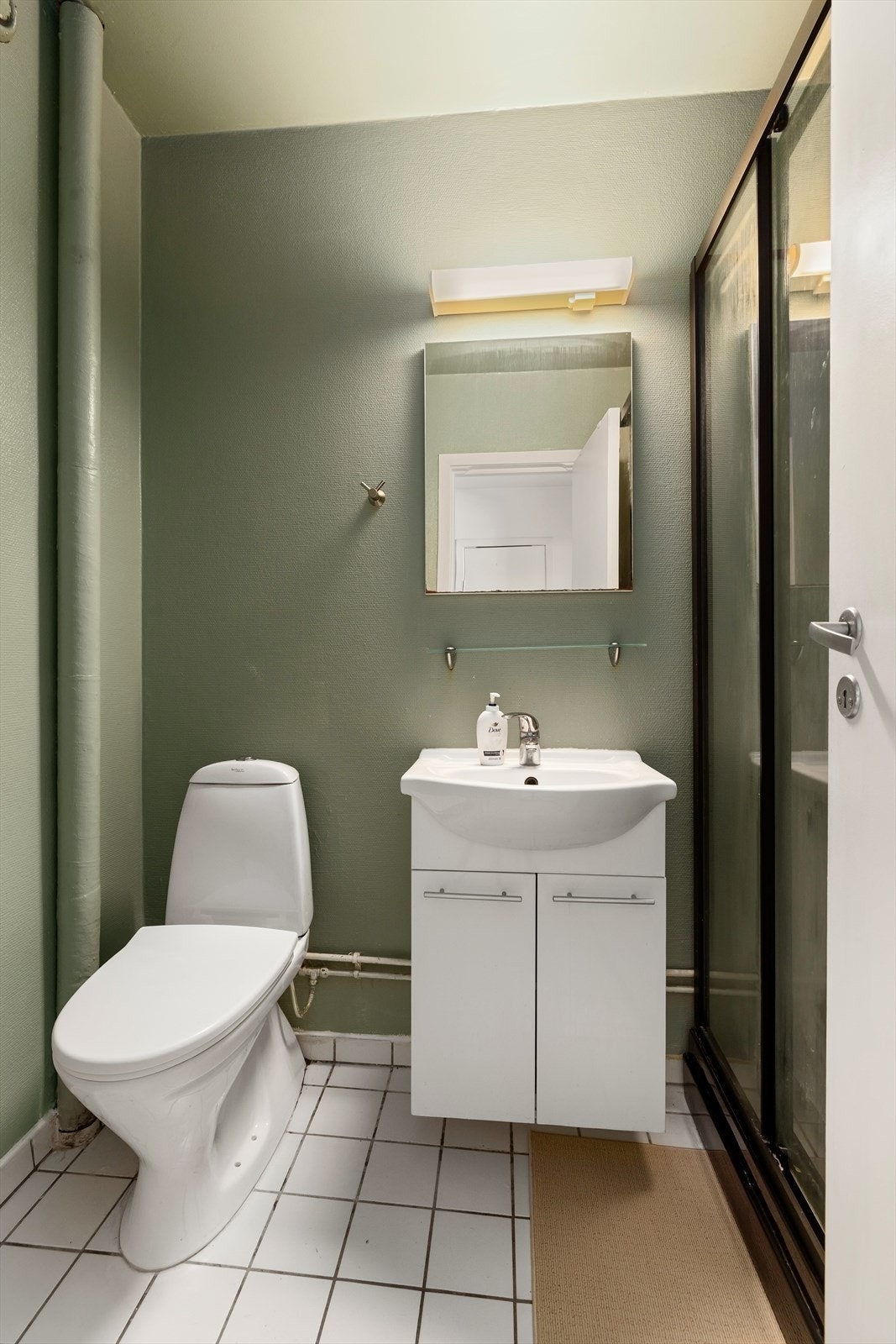 Badet har flislagt gulv, servantinnredning og toalett. Galleribilde