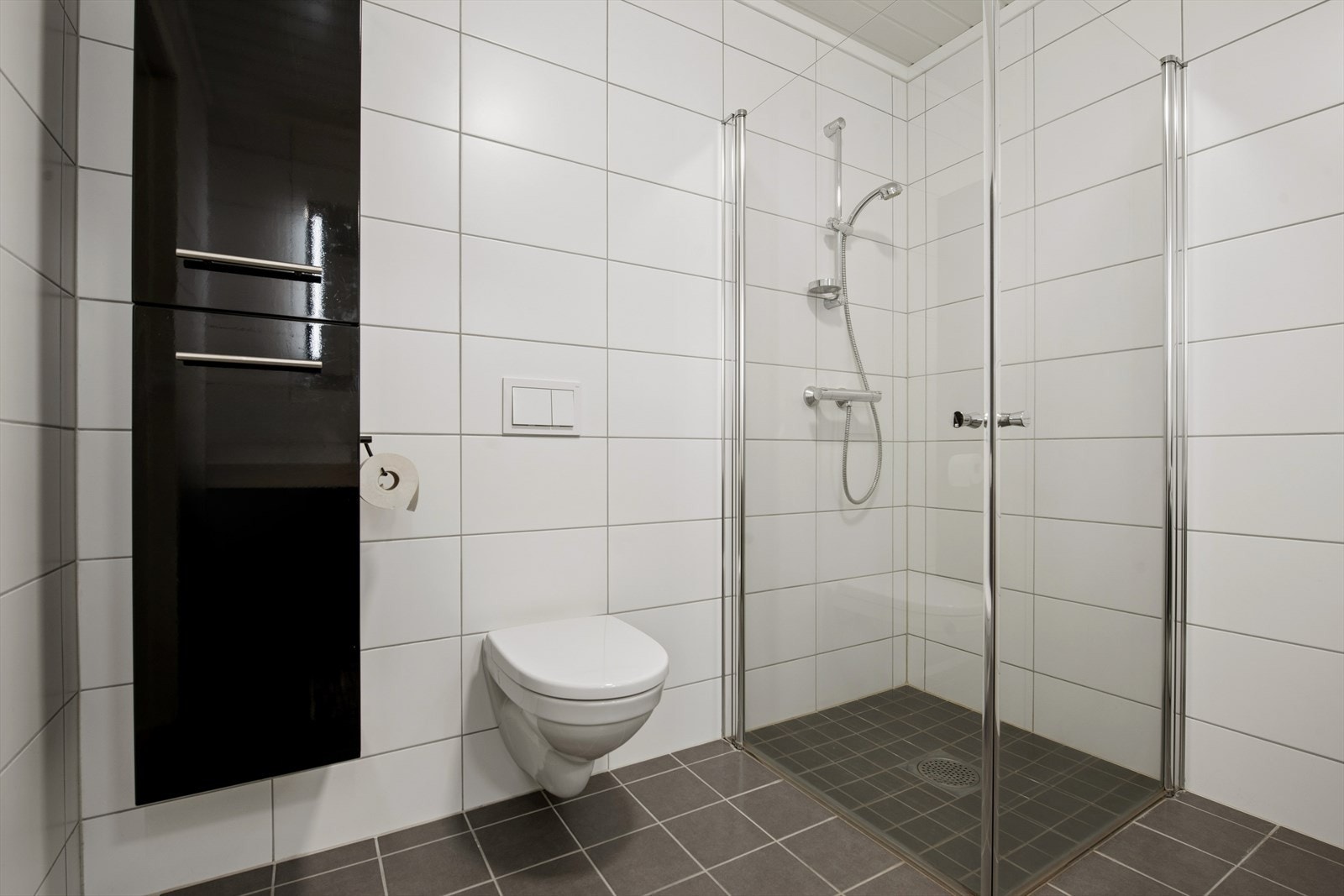 Badet har vegghengt toalett og servant med underskap for god oppbevaring. Galleribilde