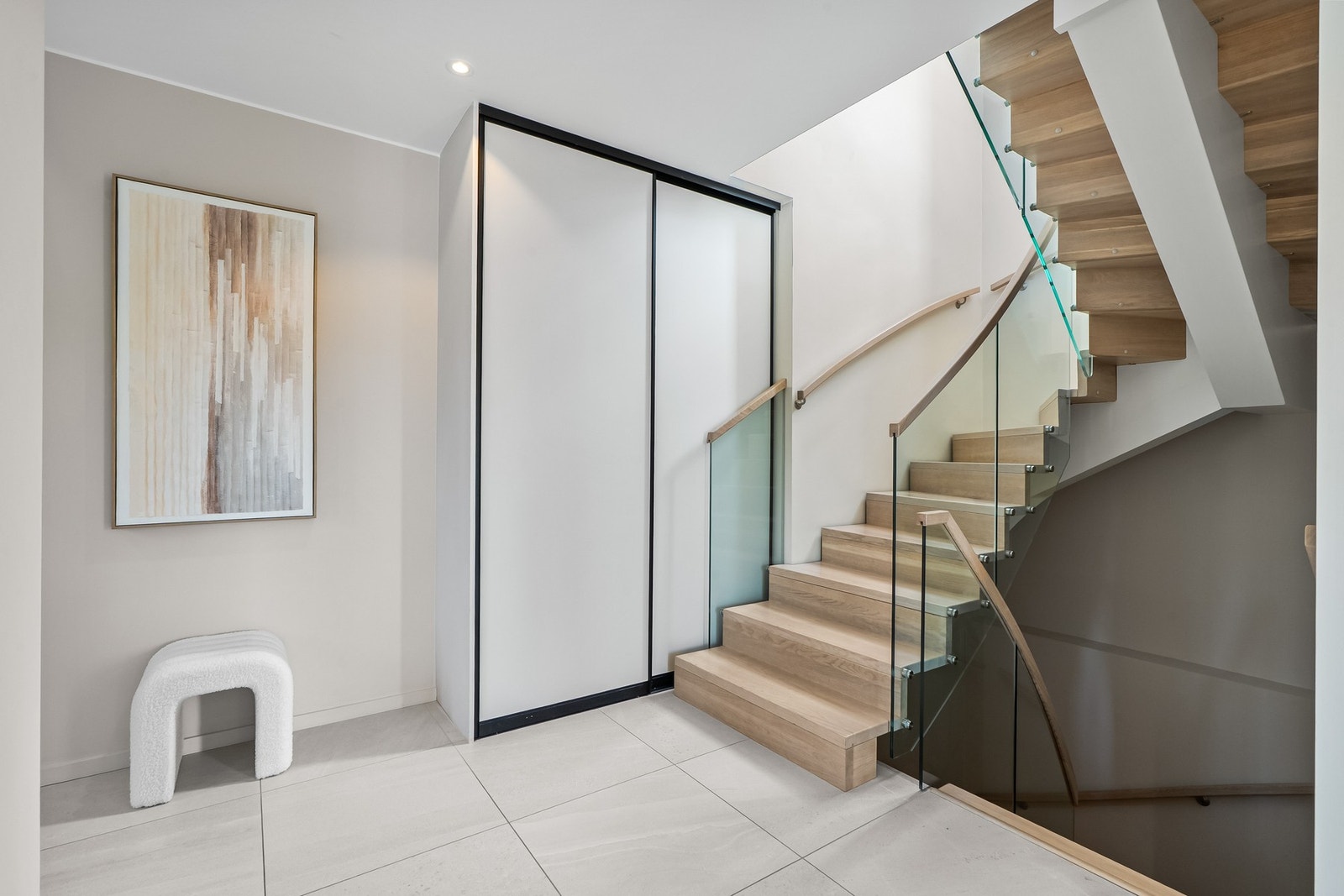 Hall/ trappegang med lekker trapp i lyst tre og glass. Gulvvarme, downlights og skyvedørsgarderobe Galleribilde