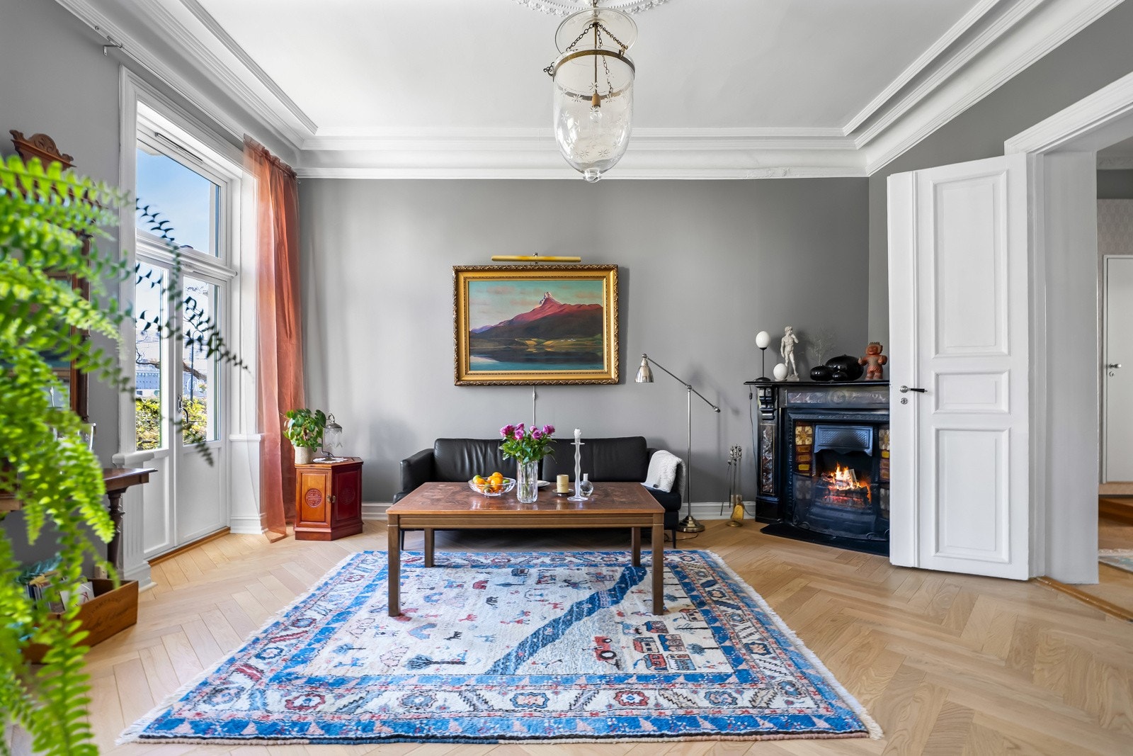 Romslig og svært innbydende stue med god takhøyde, klassiske stukkaturer og store vindusflater som gir rikelig med naturlig lys Galleribilde