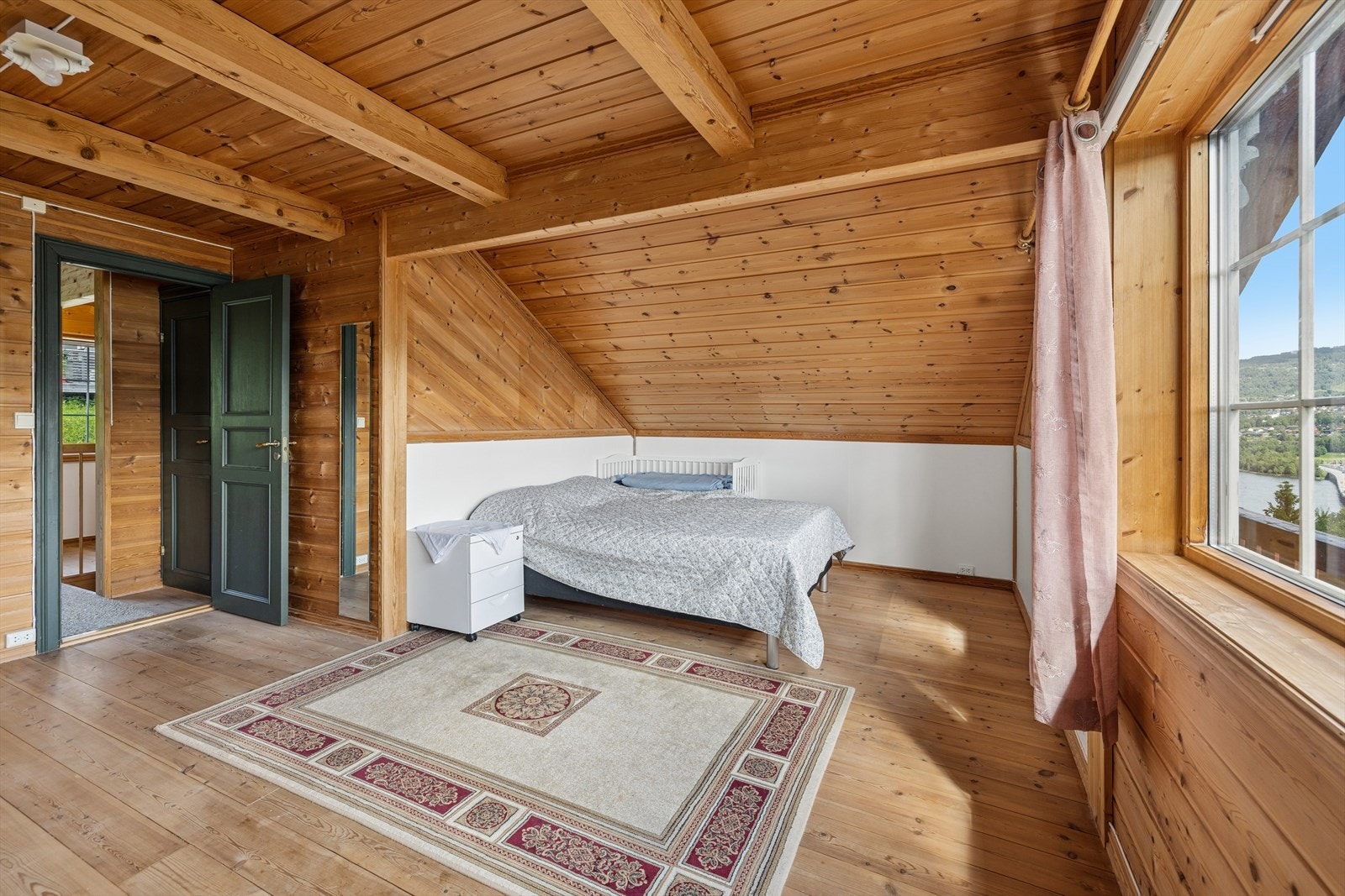 Hovedsoverommet på loftet er romslig, med panelkledde vegger og tak. Galleribilde