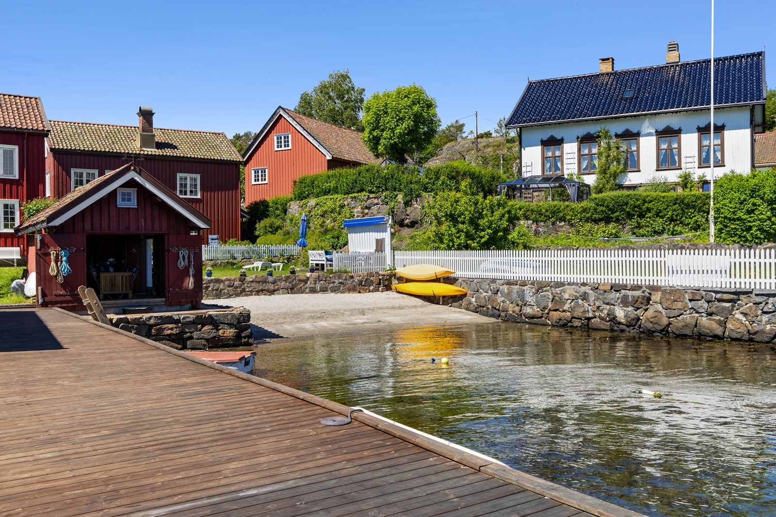 Sandstranden, sjarmerende sjøbu samt stor stenbrygge med tredekke. Galleribilde