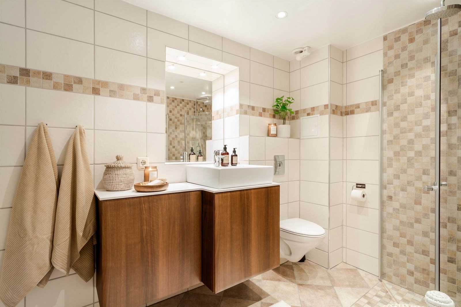 De lyse flisene kombinert med varme tretoner på innredningen gir badet et delikat og behagelig uttrykk. Galleribilde