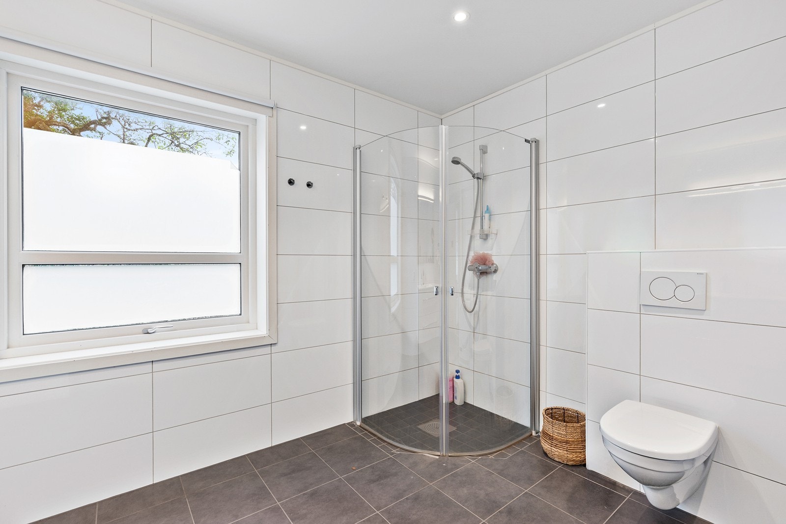 Badet har moderne innredning med vegghengt toalett, dusjhjørne og vask med skuffeinnredning. Galleribilde
