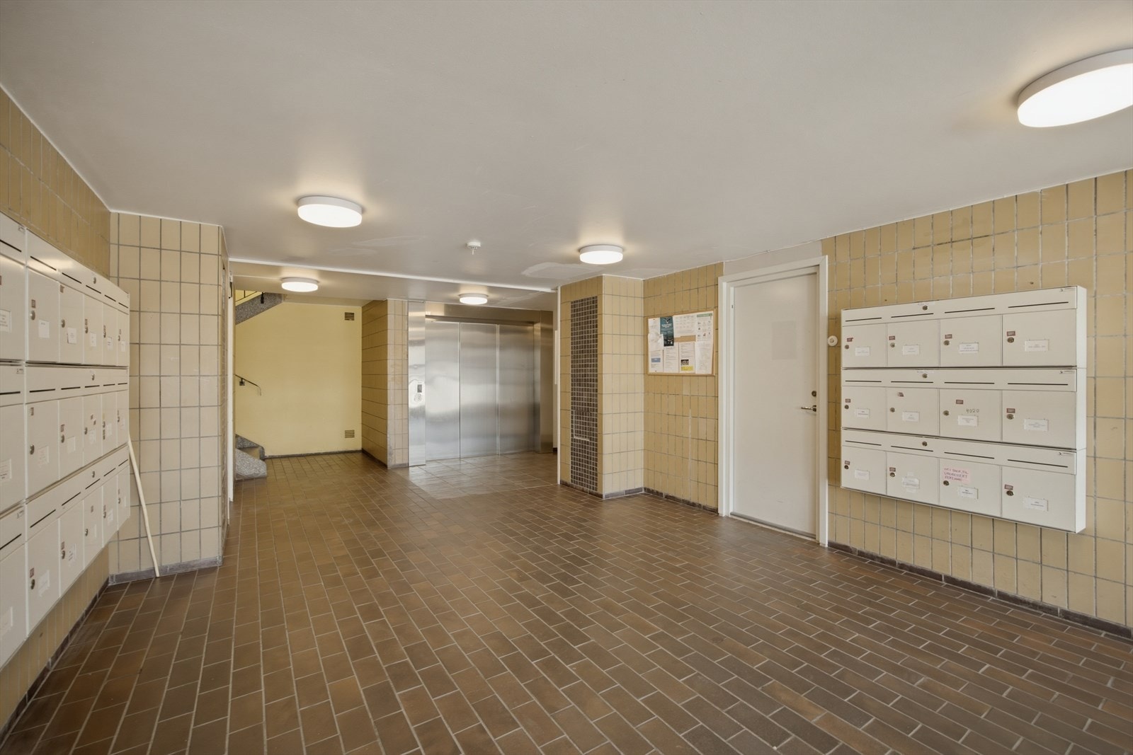 Felles inngangsparti med postkasser og heis i bygget. Gateparkering utenfor blokken. Galleribilde