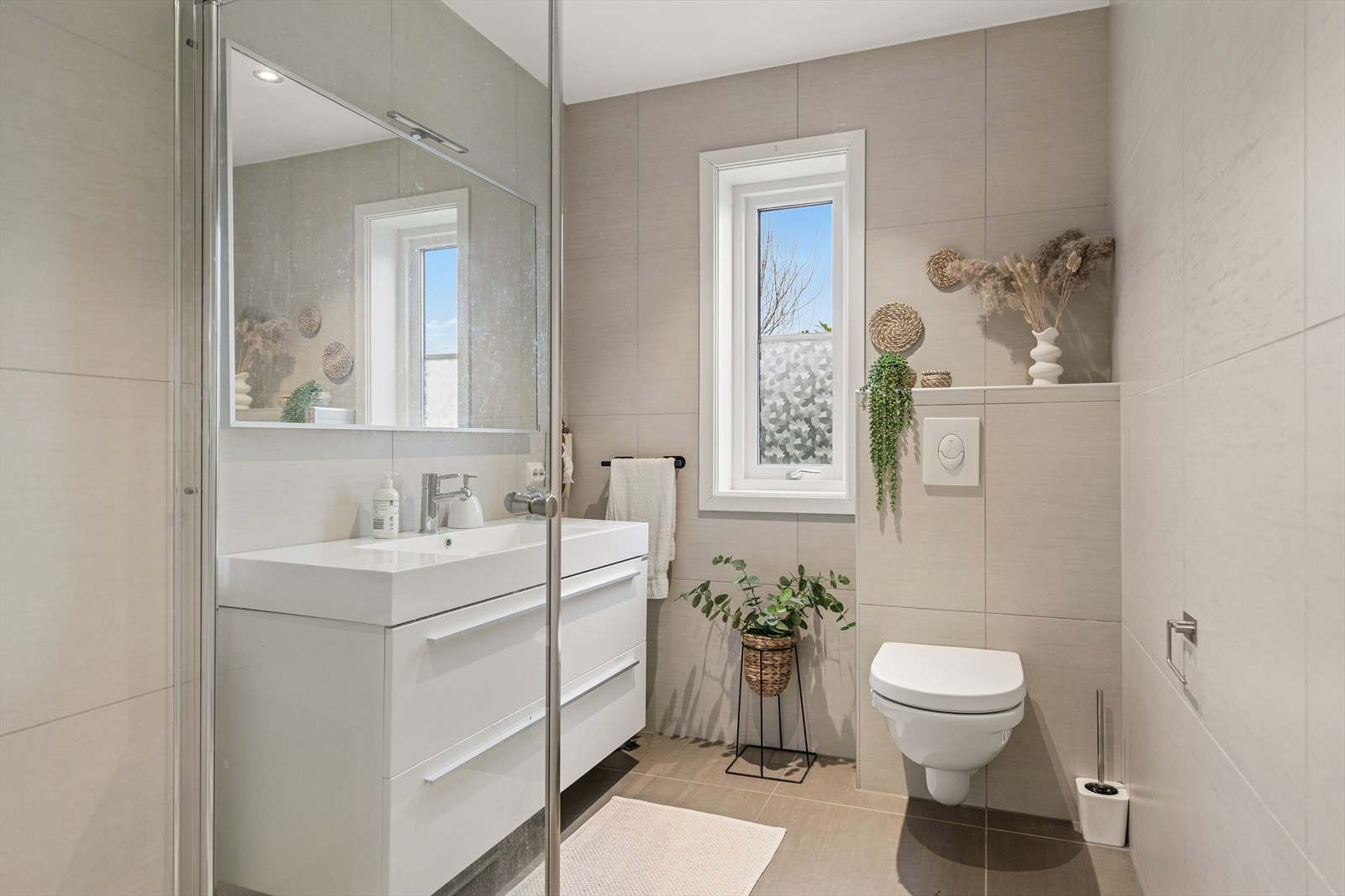 Badet i 1. etasje har flislagte overflater, dusjhjørne og veggmontert toalett. Galleribilde