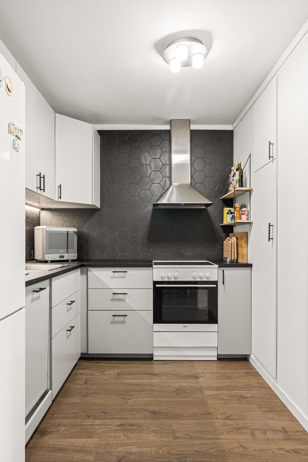 Kjøkkeninnredning med glatte fronter, laminatbenkeplate og ventilator med kullfilter. Galleribilde