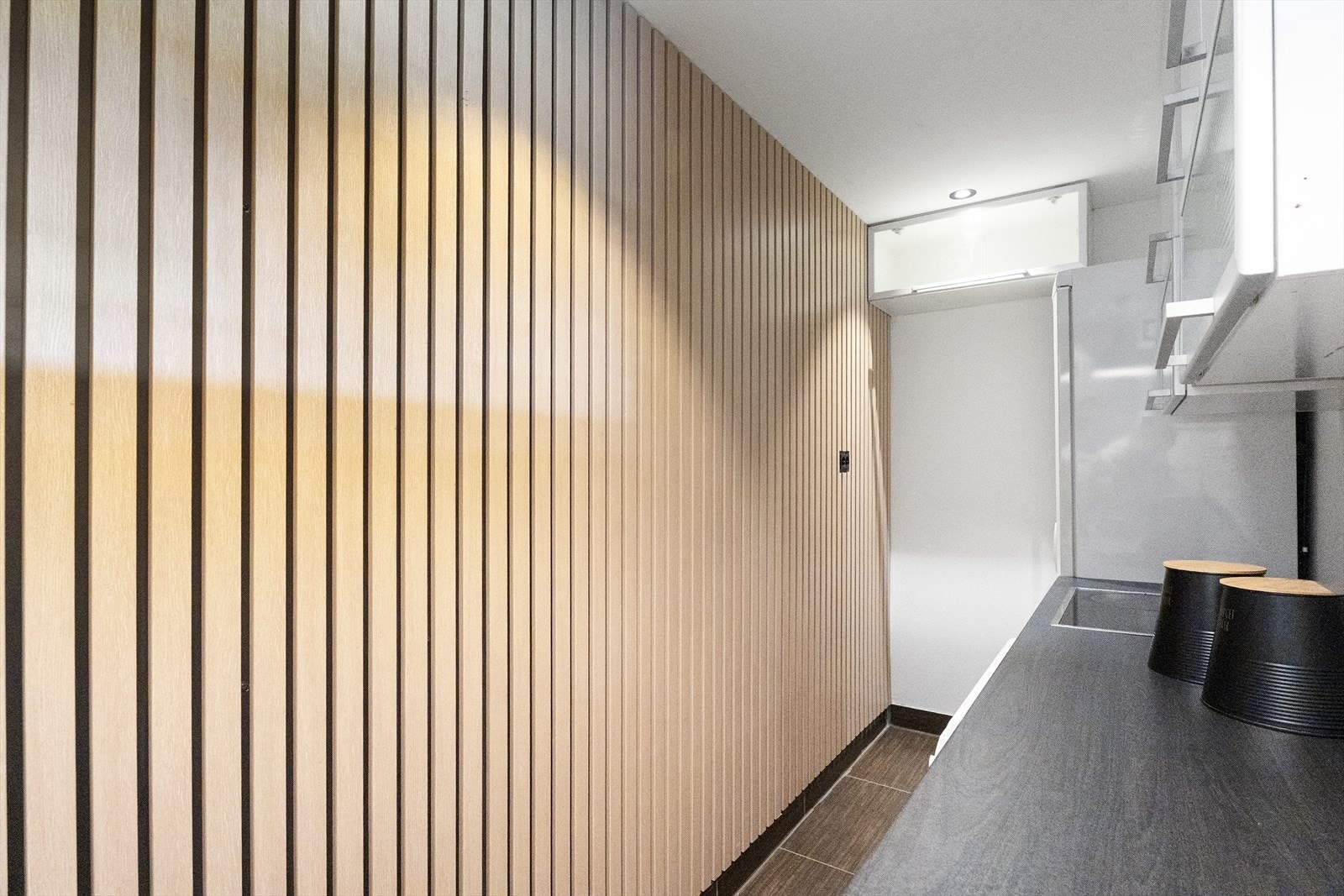 Pent og praktisk vaskerom/kjøkken som er utstyrt med platetopp, komfyr og opplegg for vaskemaskin - det er også frittstående oppvaskmaskin og kjøl/fryseskap Galleribilde