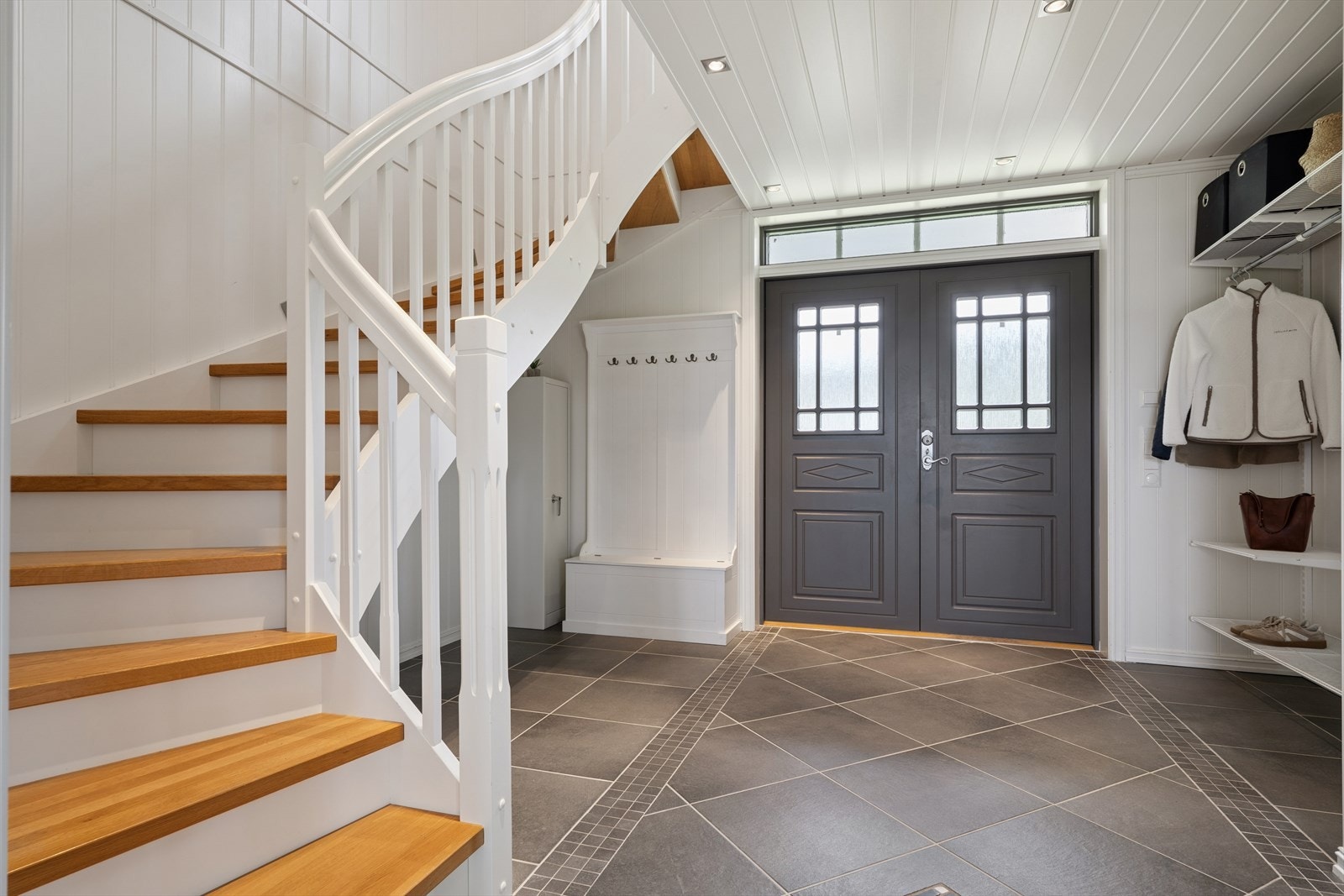 Velkommen inn! Romslig hall med flislagt gulv, vannbåren varme og en elegant, lakkert tretrapp. Galleribilde
