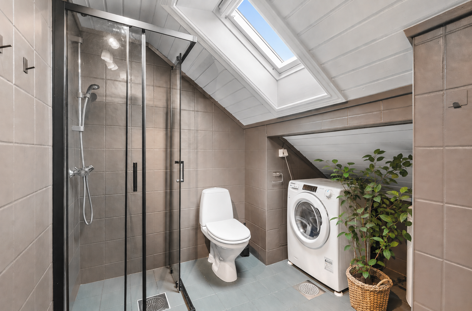 Badet innredet med dusjsone, toalett og servant med oppbevaring. Galleribilde
