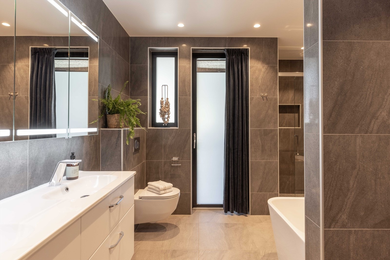 Boligen har to delikate bad, begge med gjennomførte materialvalg og moderne uttrykk. Fra badet er det direkte utgang til terrasse og jacuzzi, noe som gir en særegen spa-følelse i hverdagen. Galleribilde