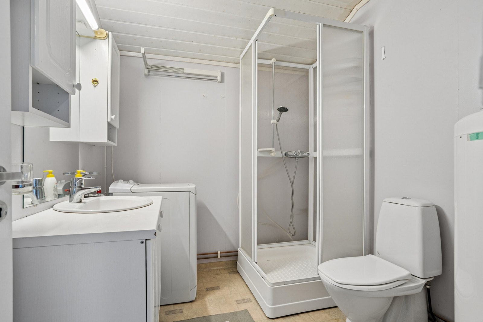 Badet er utstyrt med dusjkabinett, toalett, innredning og opplegg for vaskemaskin. Galleribilde