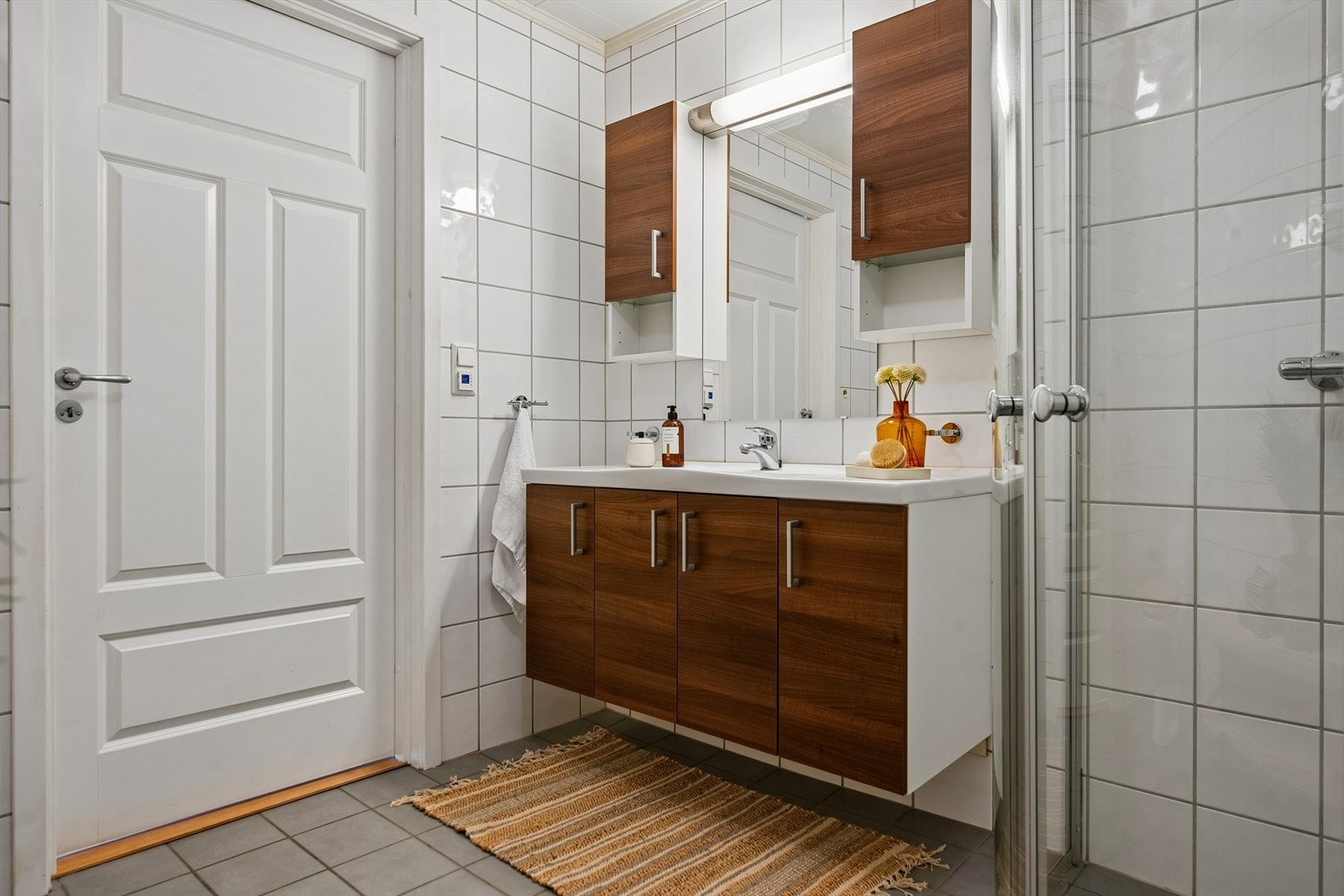 Badet har fliser på gulv og vegger, servant med underskap og speil med belysning. Galleribilde