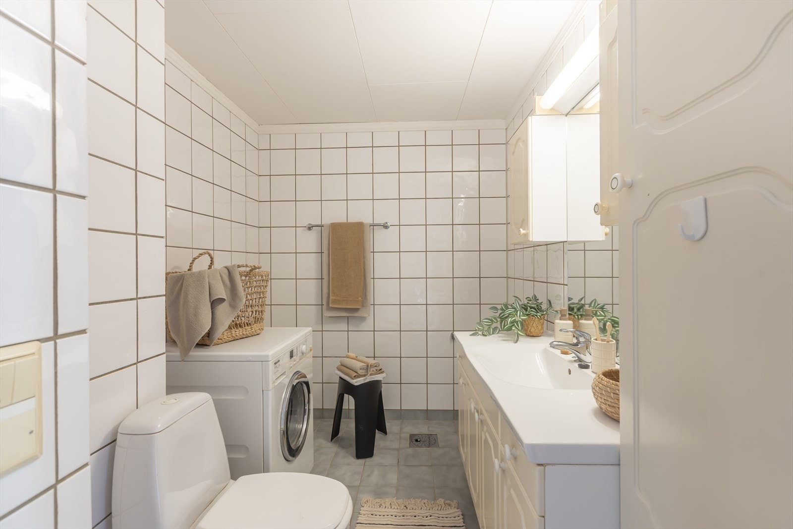 Baderommet med flislagte vegger og gulv. Opplegg vaskemaskin. Foto: GMP Galleribilde