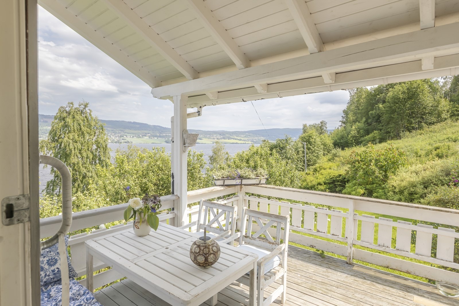 Fra verandaen kan du nyte utsikten over den parklignende hagen, Randsfjorden og det vakre landskapet som omgir eiendommen. Foto: GMP Galleribilde