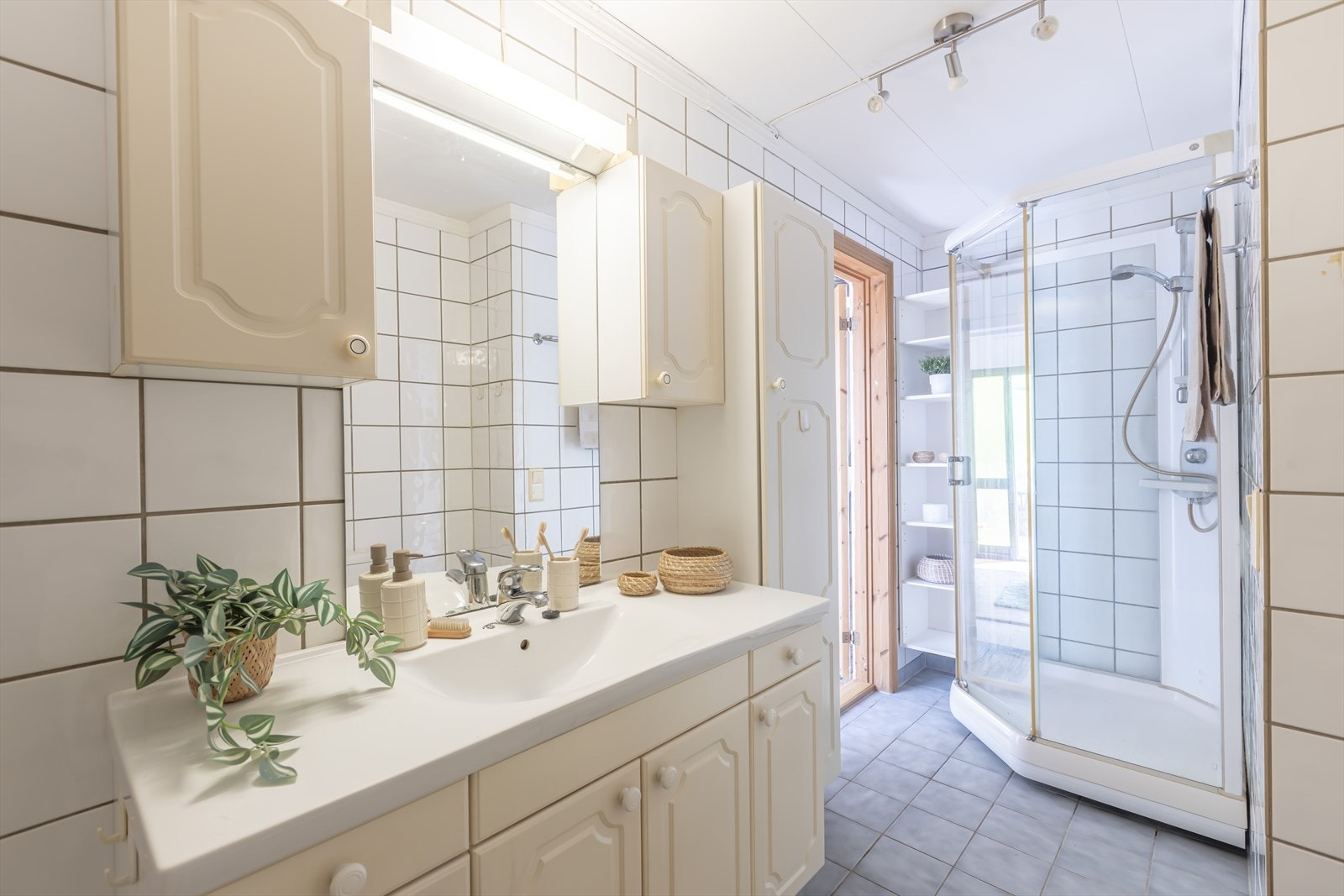 Badet fremstår funksjonelt og innbydende, med dusjkabinett, baderomsinnredning med nedfelt servant og rikelig med skapplass for praktisk oppbevaring. Foto: GMP Galleribilde