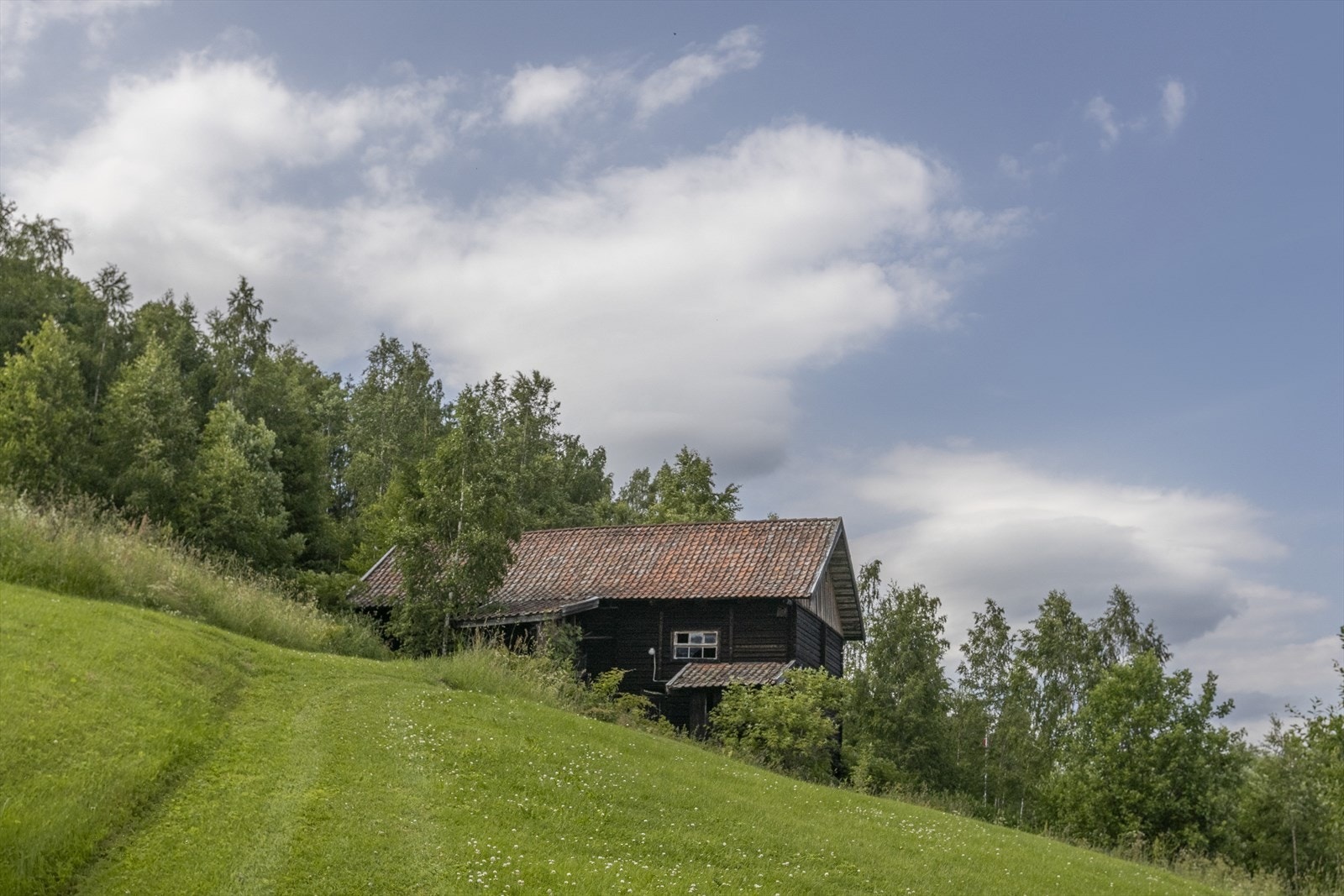 På tunet ligger en eldre tømmerlåve over tre plan, som tidligere har vært benyttet til husdyrhold. Bygningen gir i dag spennende muligheter for videre bruk. Foto: GMP Galleribilde