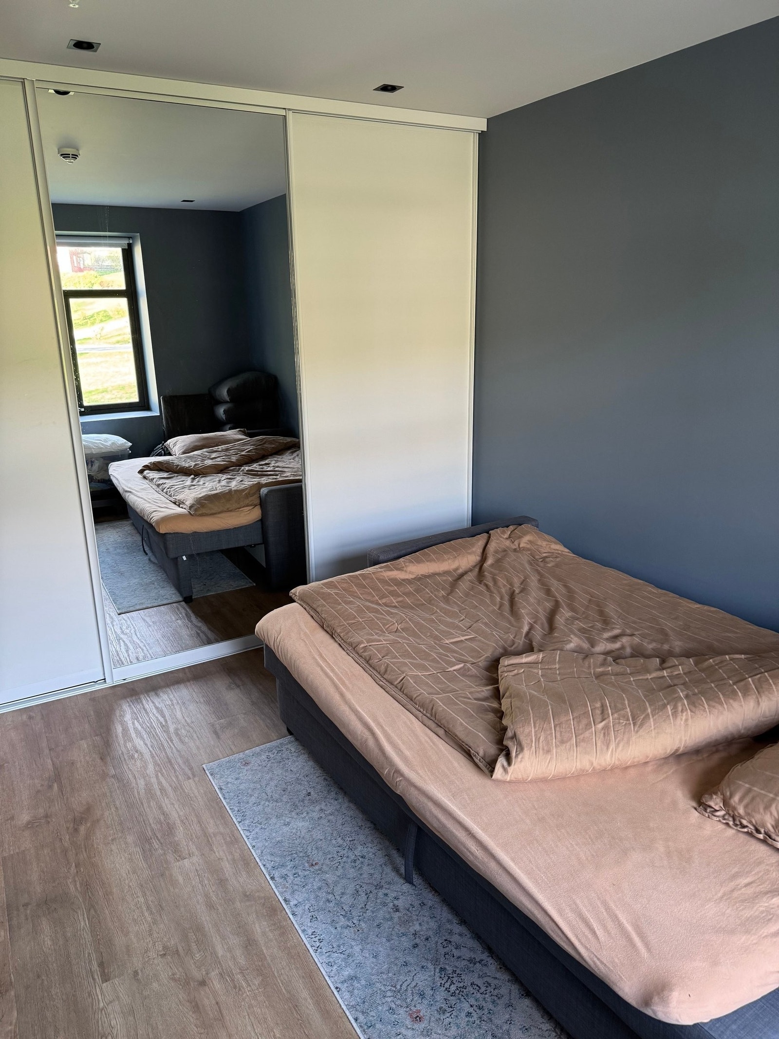 Stilrent og romslig soverom med praktisk skyvedørsgarderobe. Galleribilde