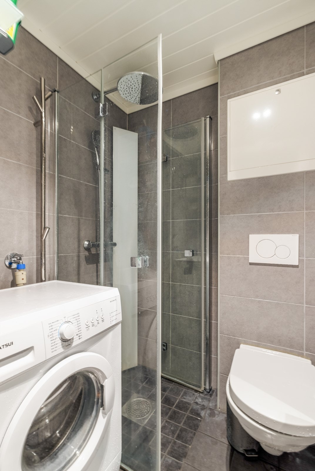 Dusjnisjen har plassbesparende, innfellbare glassdører, og det er dusjgarnityr på vegg med både hånddusj og takdusj. Badet har også opplegg for og plass til vaskemaskin. Galleribilde