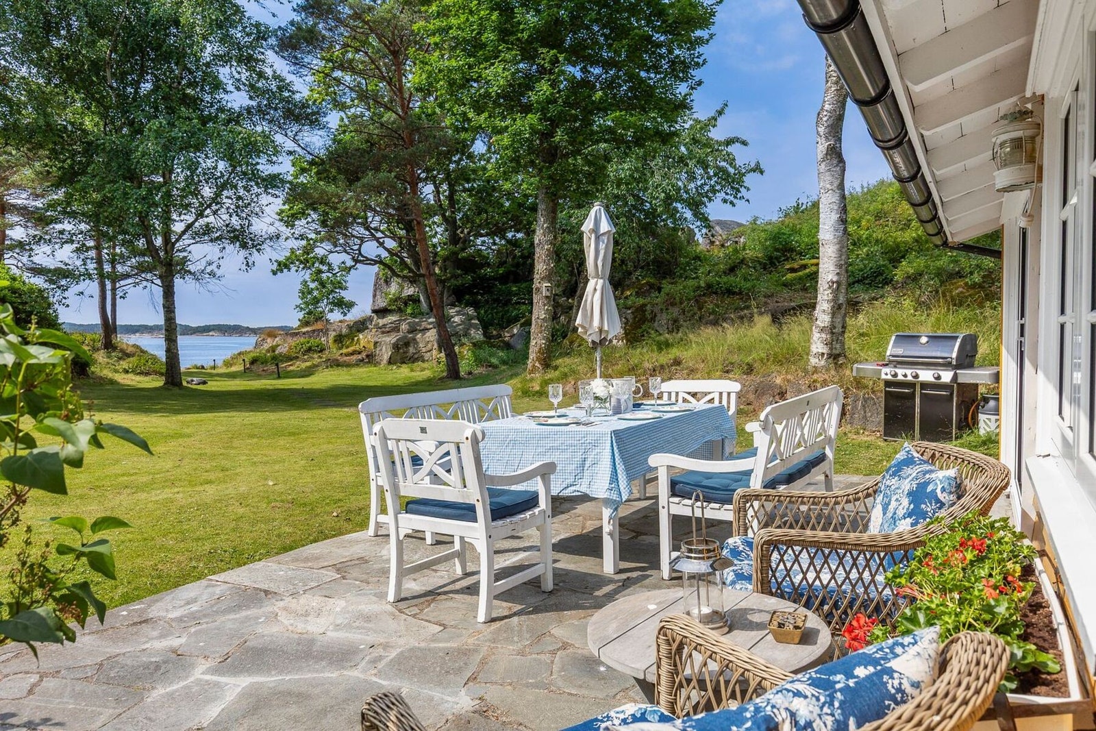 Stor, solrik terrasse med utsikt mot hagen og sjøen. Galleribilde
