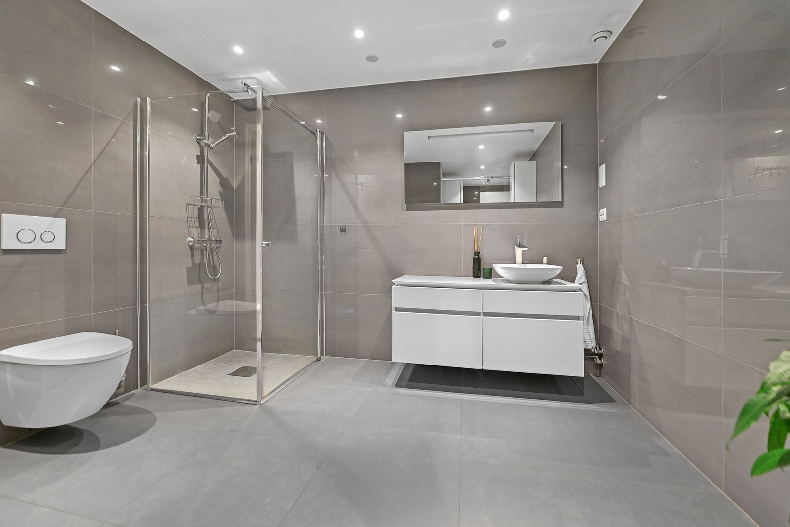 Nede ble badet pusset opp i 2015, innredet med store, grå fliser for en moderne finish. Galleribilde