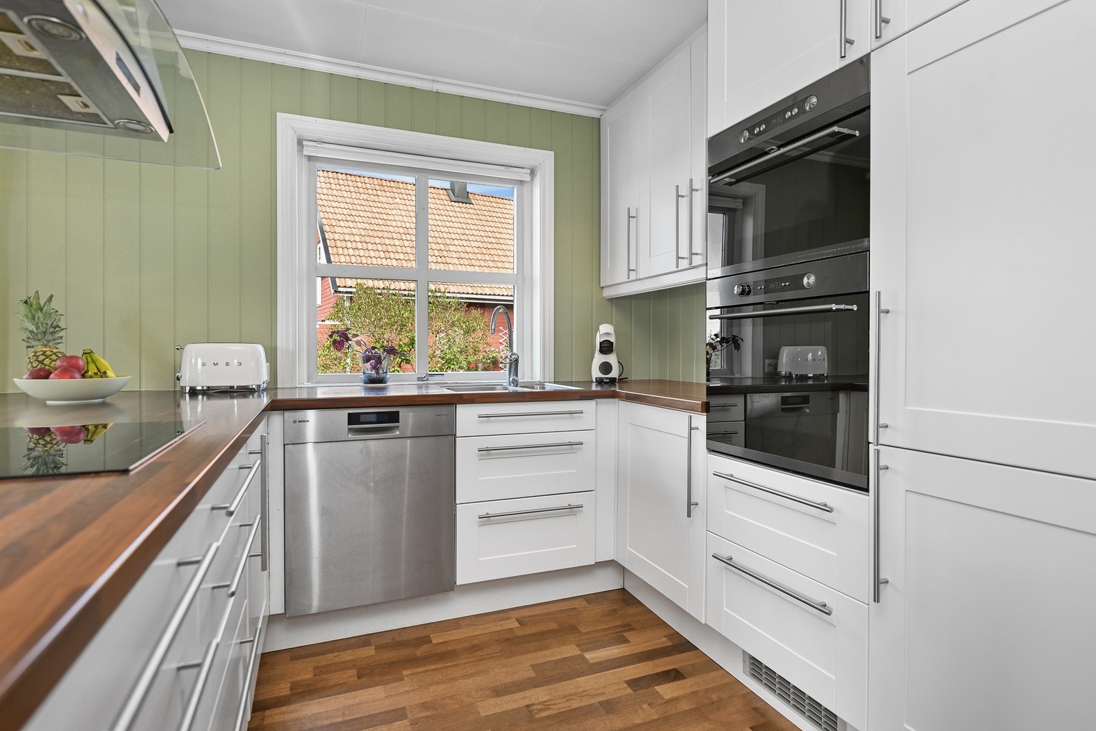 Innredningen har hvite, profilerte fronter, vitrineskap under baren, benkeplate av laminat og dobbel oppvaskkum i stål. Galleribilde