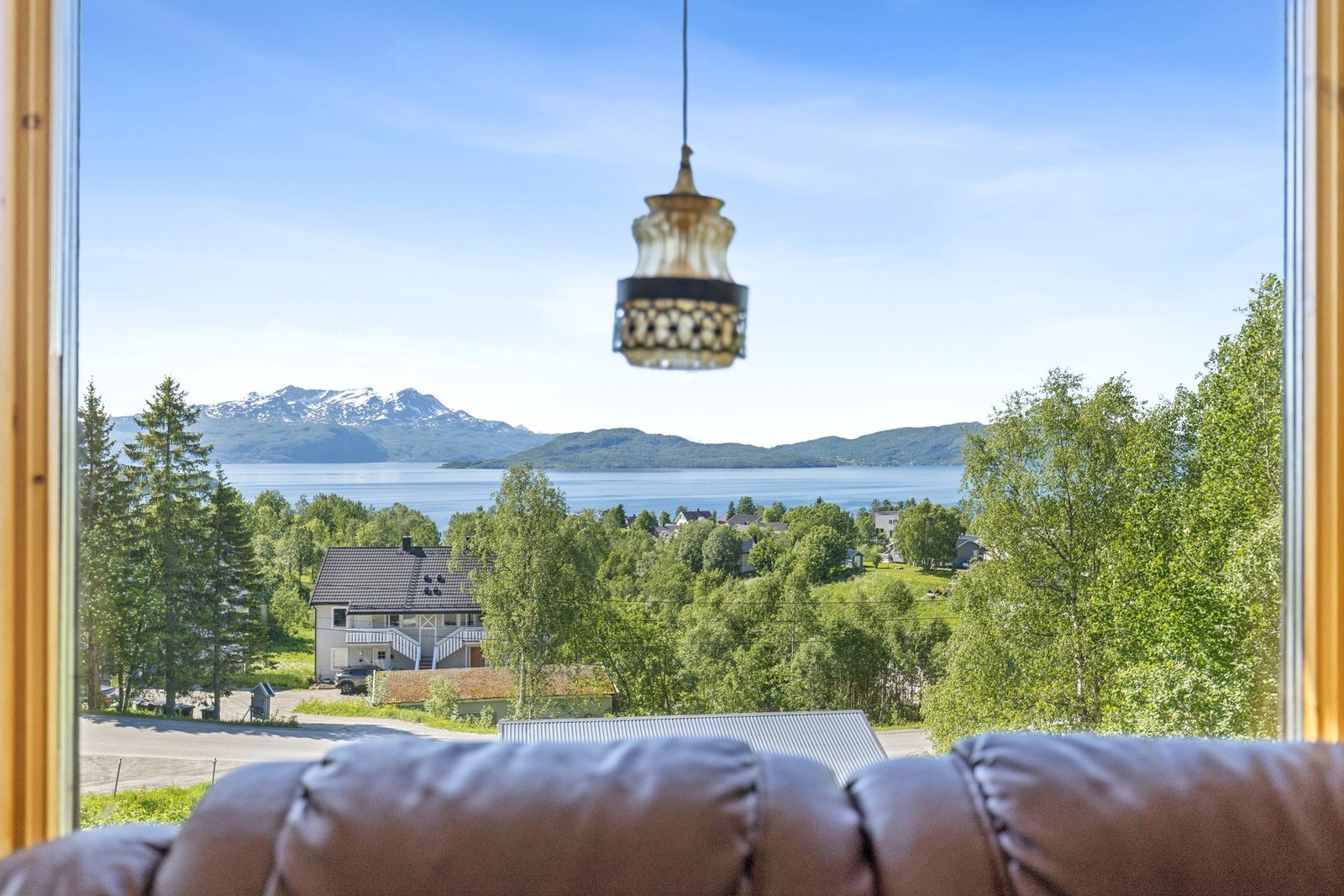 Utsikten strekker seg over nærområdet, fjorden og fjellene i horisonten. Galleribilde