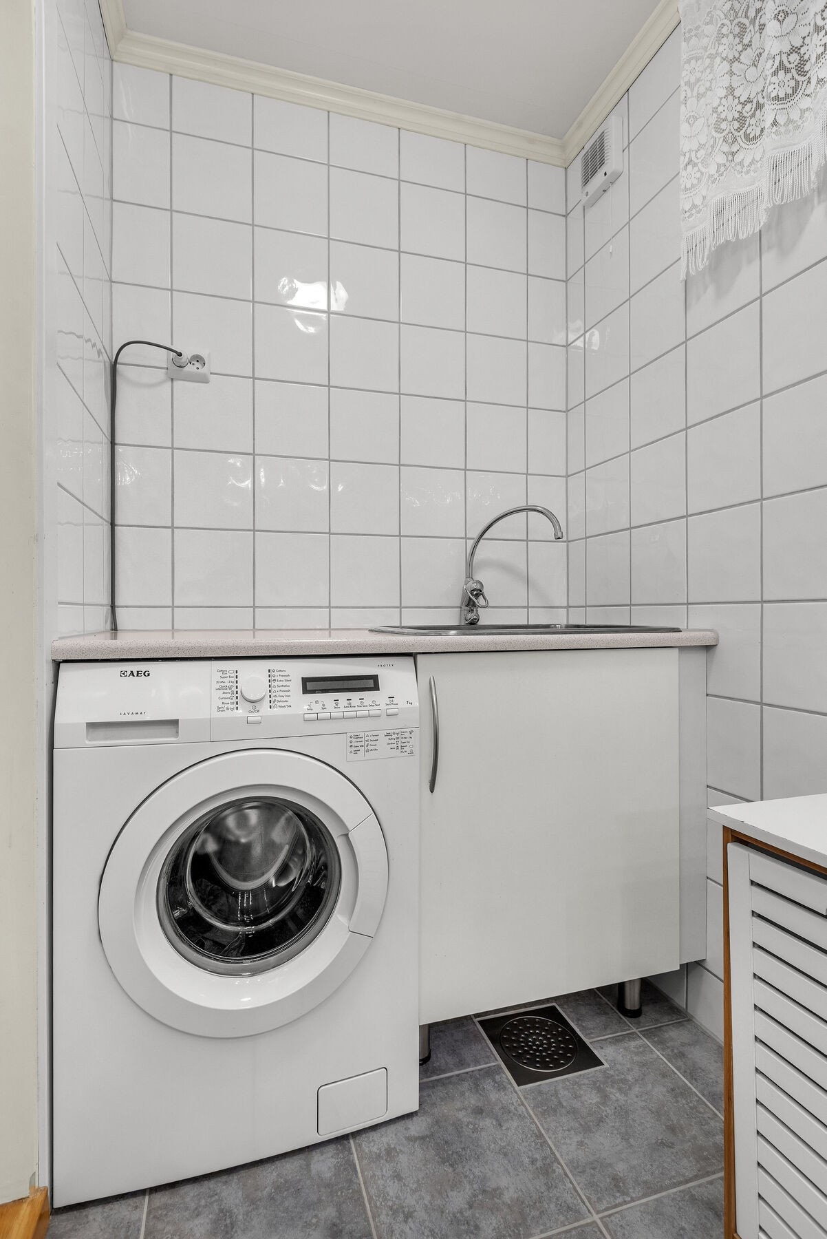 Praktisk vaskerom med flislagt gulv med varmekabler og opplegg for vaskemaskin. Galleribilde