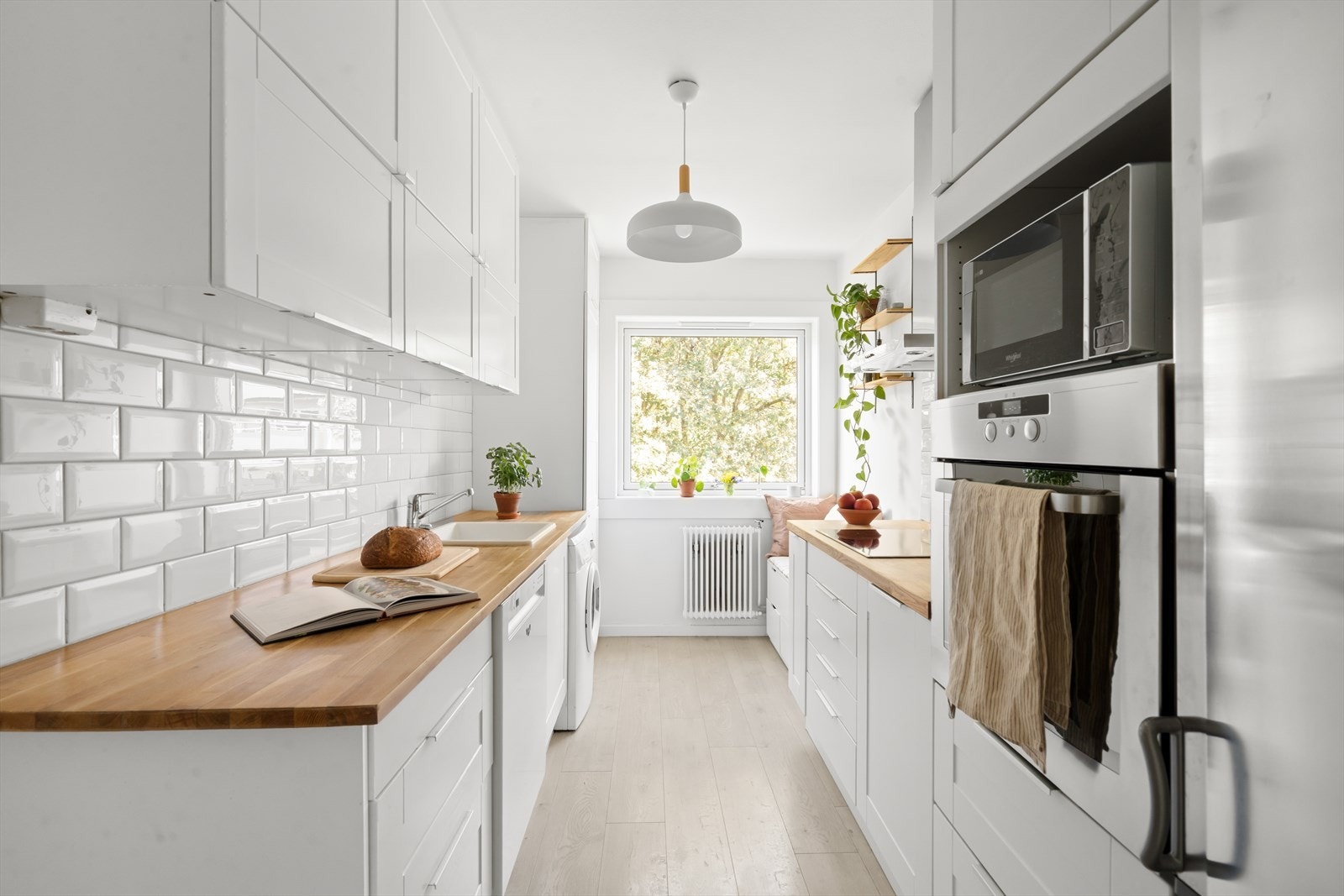 IKEA kjøkkeninnredning fra 2016 med malte 1-speils fronter, benkeplate i tre med nedfelt kum i keramikk, fliser på vegg over benk og ventilator med kullfilter. Galleribilde