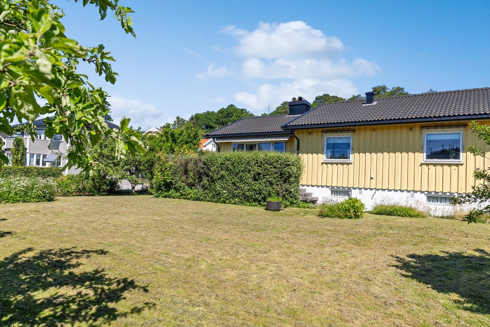 Den relativt flate tomten er pent opparbeidet med store plenarealer og variert beplantning, noe som skaper et trivelig og innbydende uteområde med mange bruksmuligheter. Galleribilde