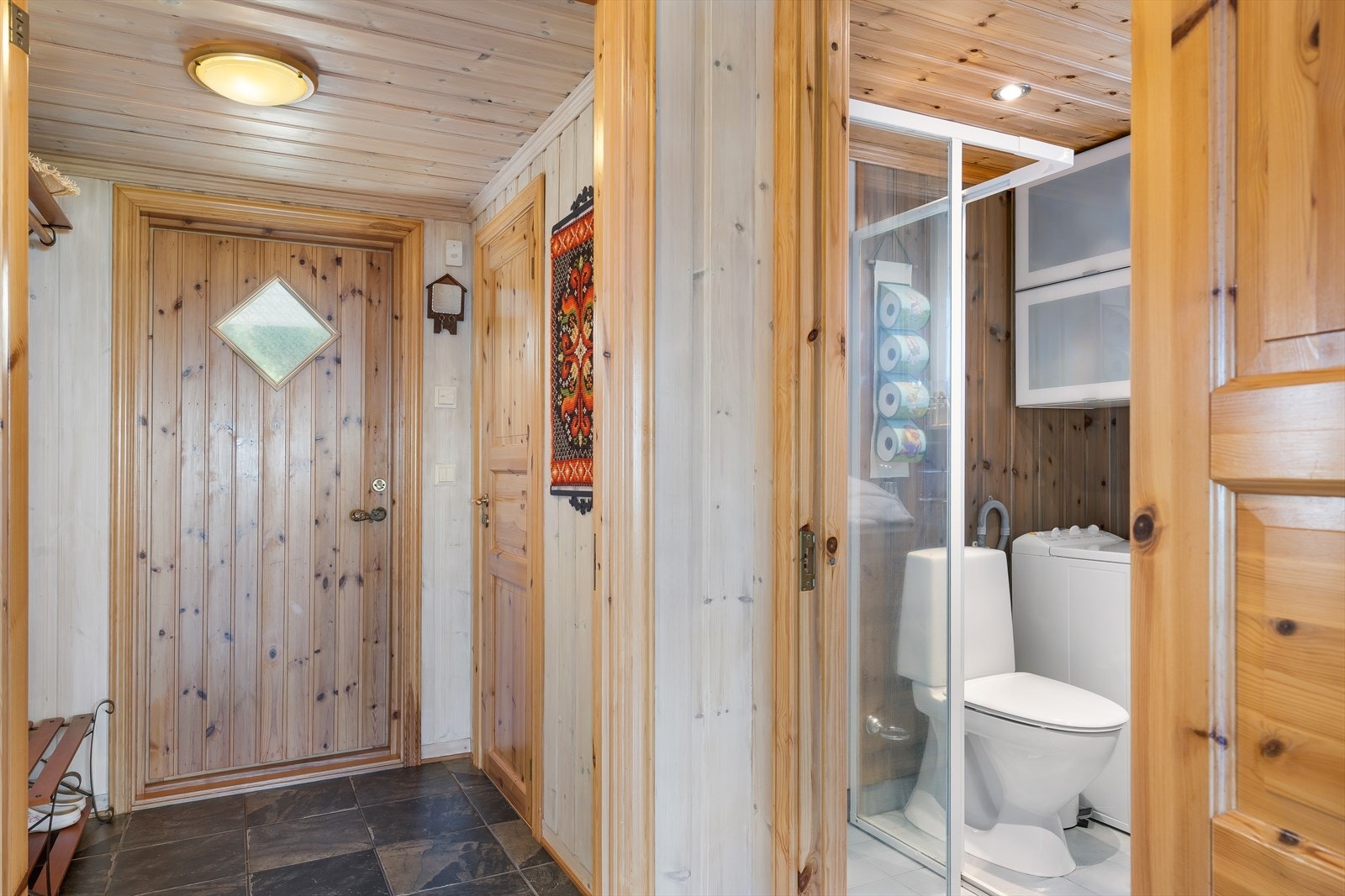 Badet er praktisk innredet med toalett, dusjkabinett og vaskemaskinopplegg. Galleribilde