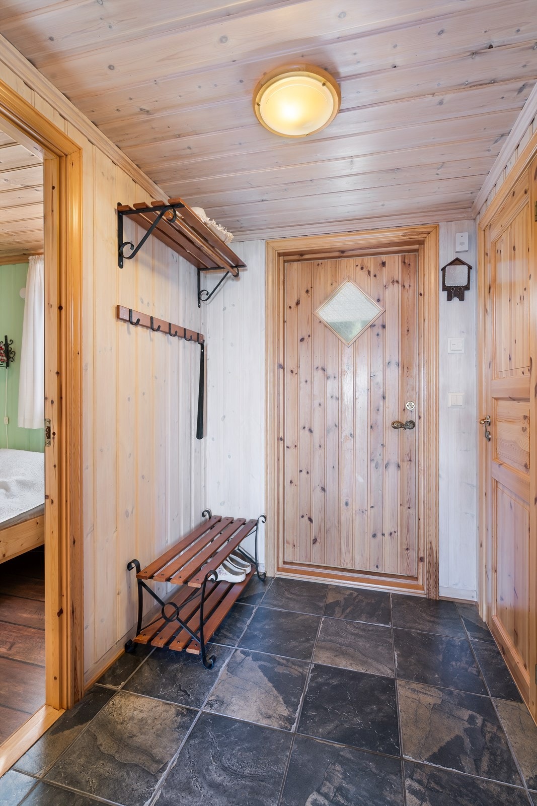 Entréen har flislagt gulv og panelte vegger, med plass til oppbevaring av yttertøy. Galleribilde
