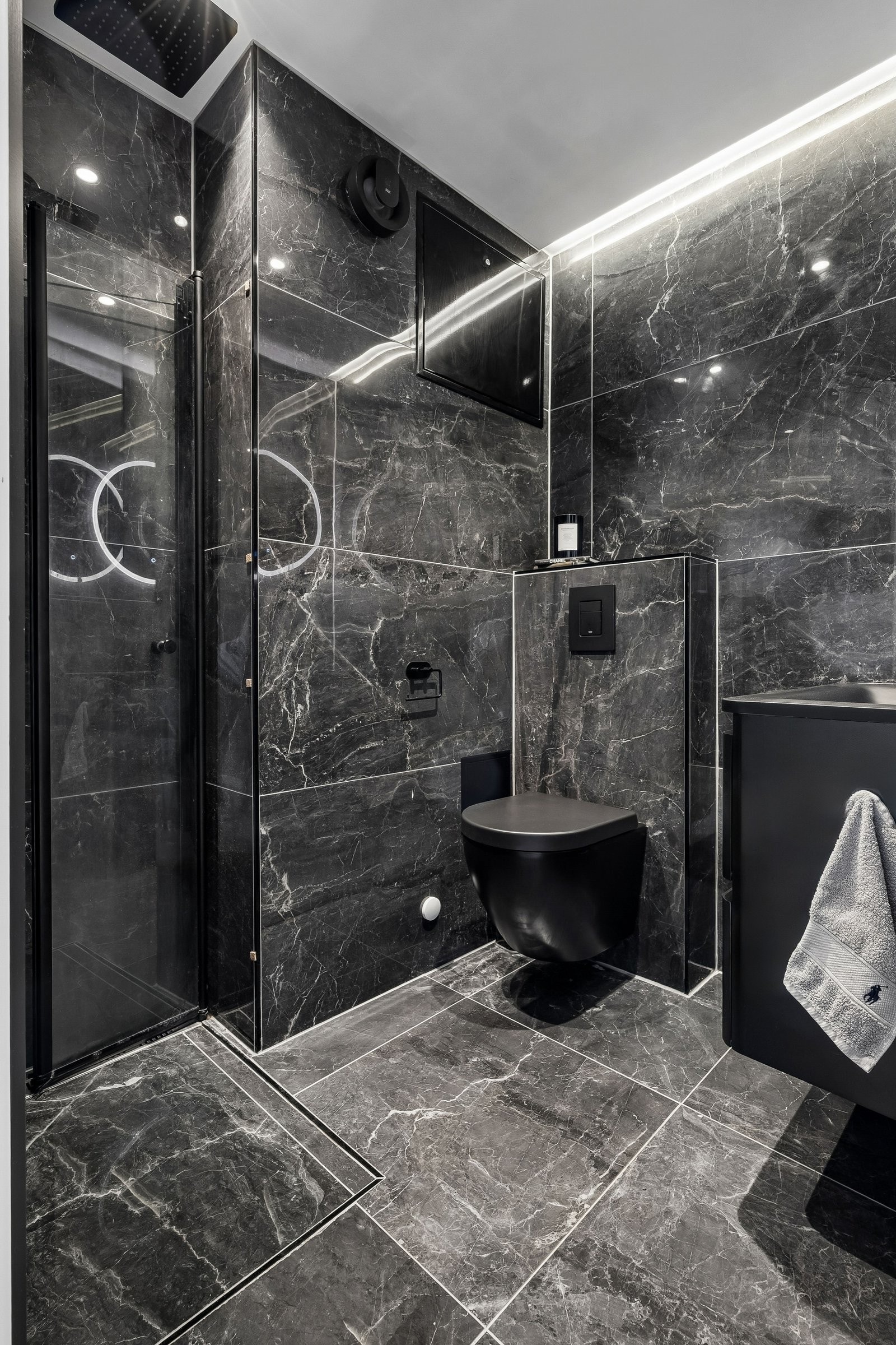 Nydelig bad med elegante detaljer i svart marmor. Dusjhjørne med sammenleggbare glassdører gir en luftigere løsning og bedre plass på badet. Galleribilde