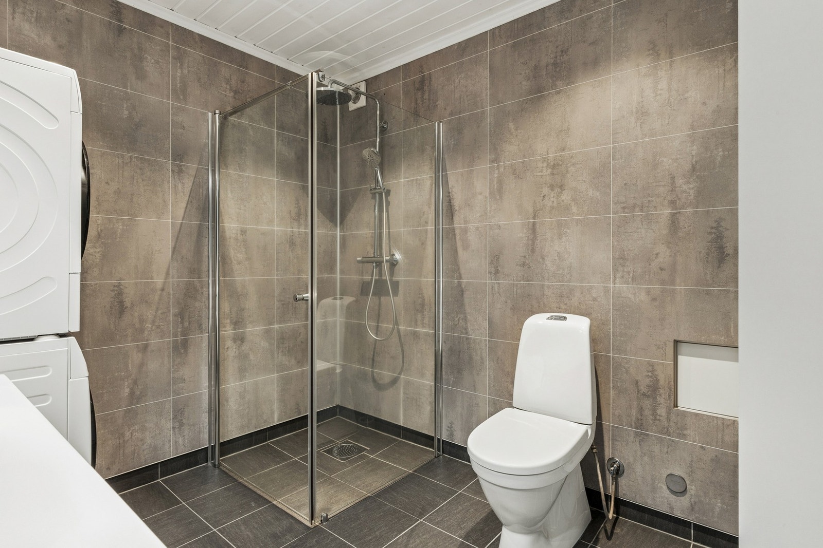 Badet er flislagt med varmekabler i gulv, og har dusjhjørne med glassvegger og regndusj. Galleribilde