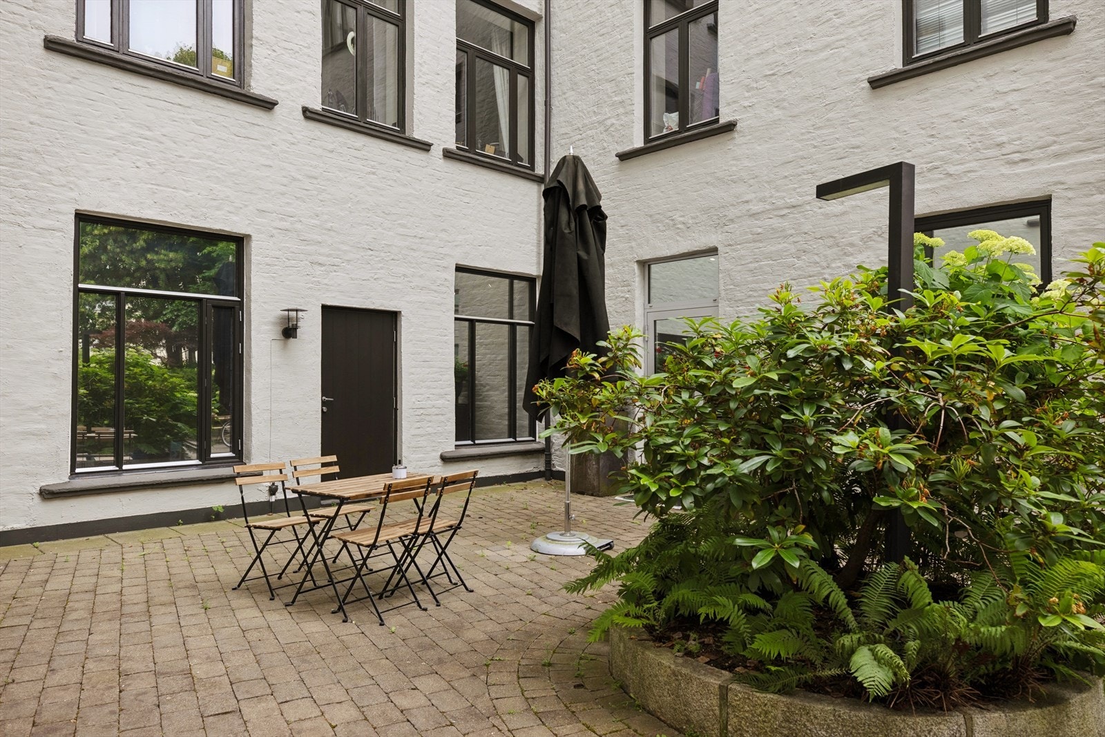 Felles skjermet bakgård med beplantning og sittegrupper. Galleribilde