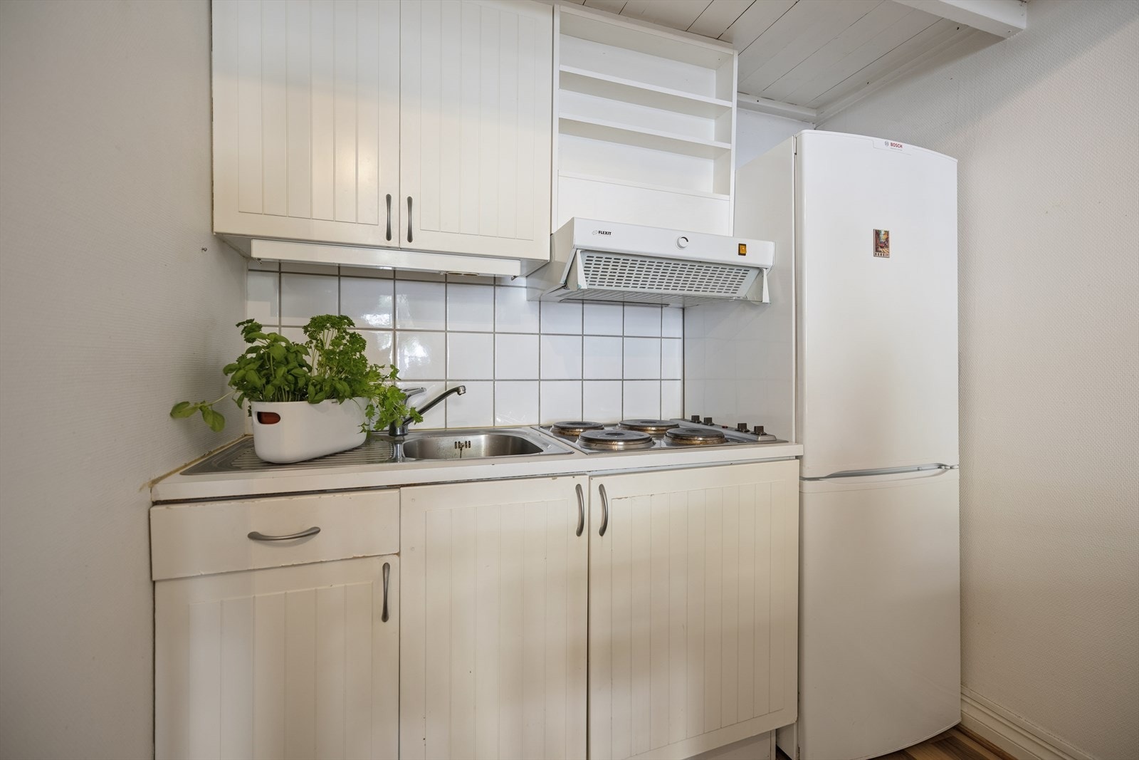 Kjøkkenet er innredet med profilerte fronter og laminat benkeplate med nedfelt kum i rustfritt stål. Galleribilde