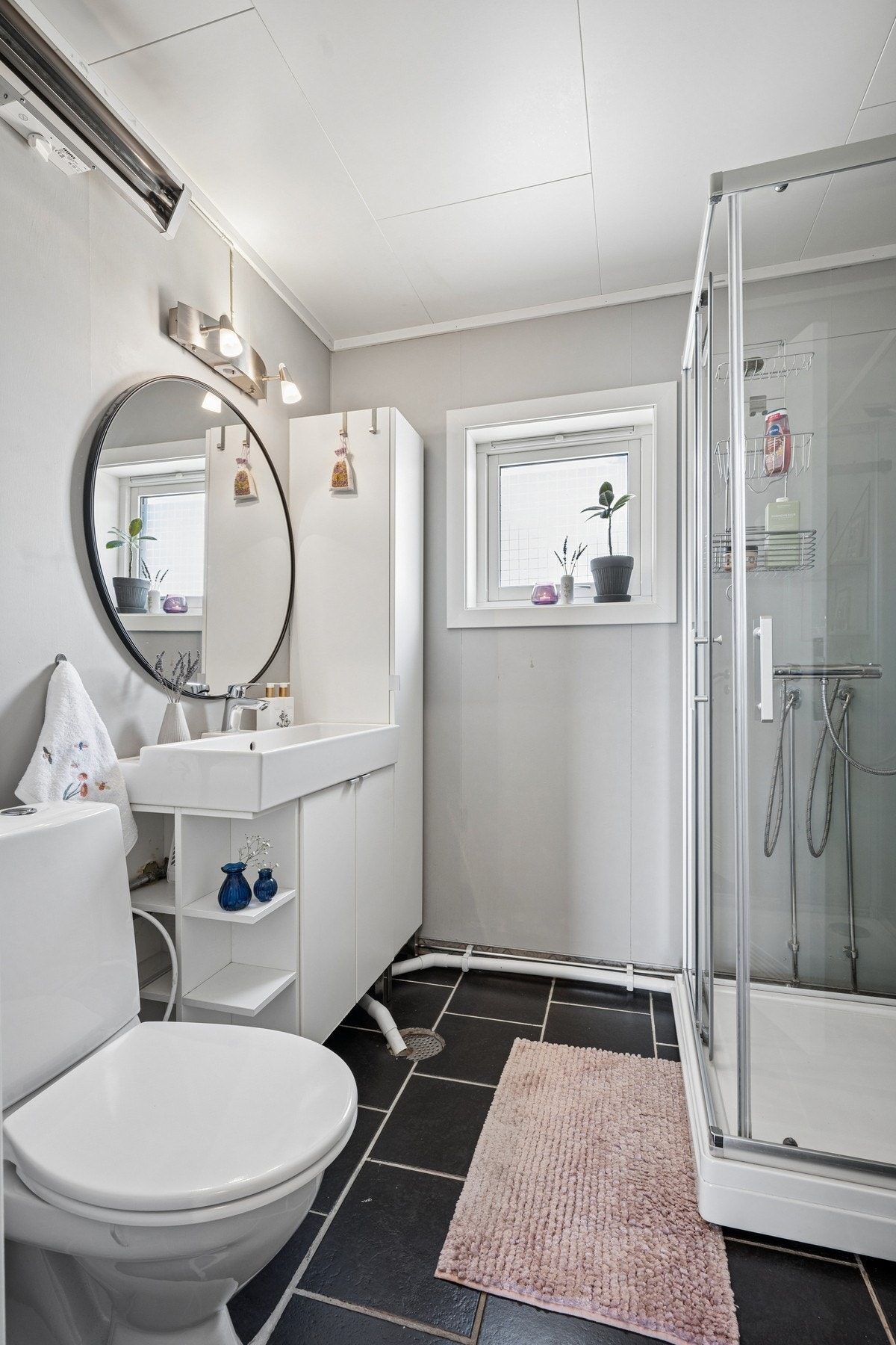 Badet har flislagt gulv, våtromsplater på veggene og panelovn. Galleribilde